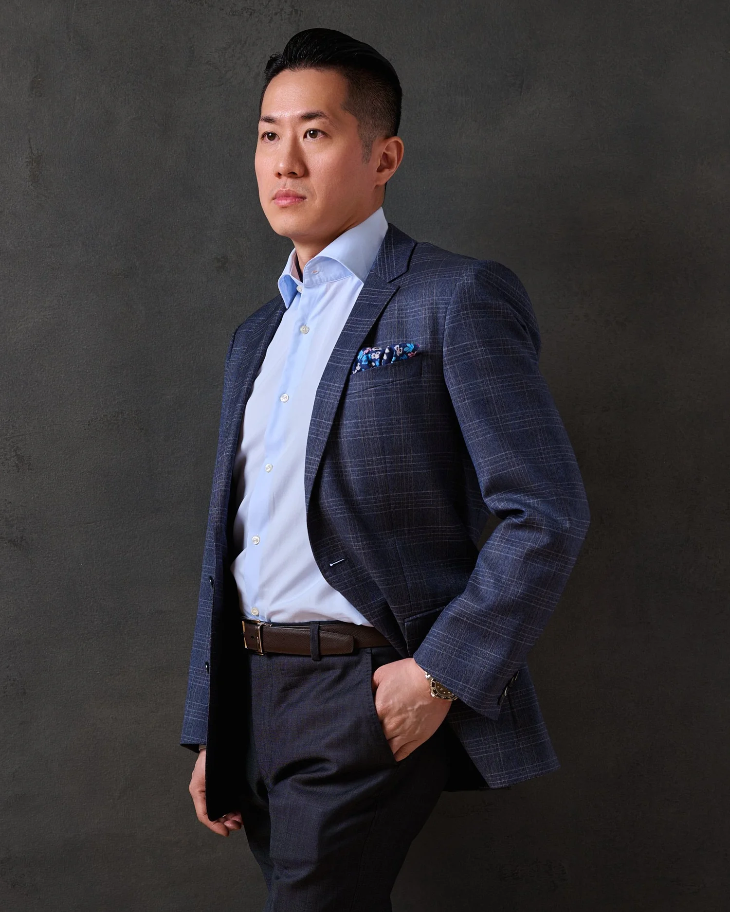 Color portrait of a man in a navy suit standing on a dark ground