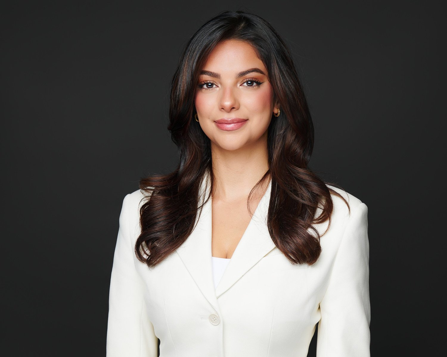 Color headshot of a woman in an ivory jacket on a dark ground, photographed by Ryan Dunbar