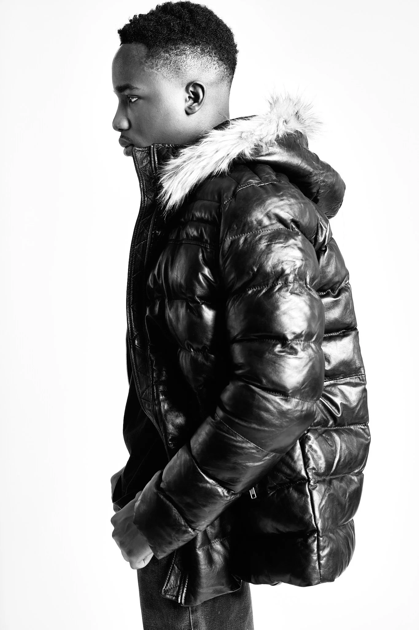 A model in profile in a fur-hooded puffer jacket for FAD Closet, black and white