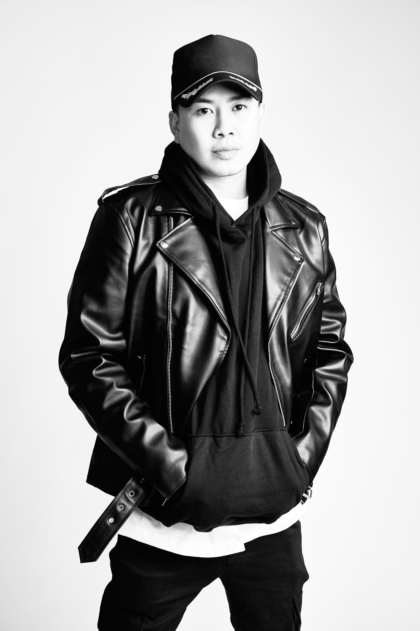 Adrian, co-owner of Far From Ordinary, in a cap and leather biker jacket, black and white studio portrait