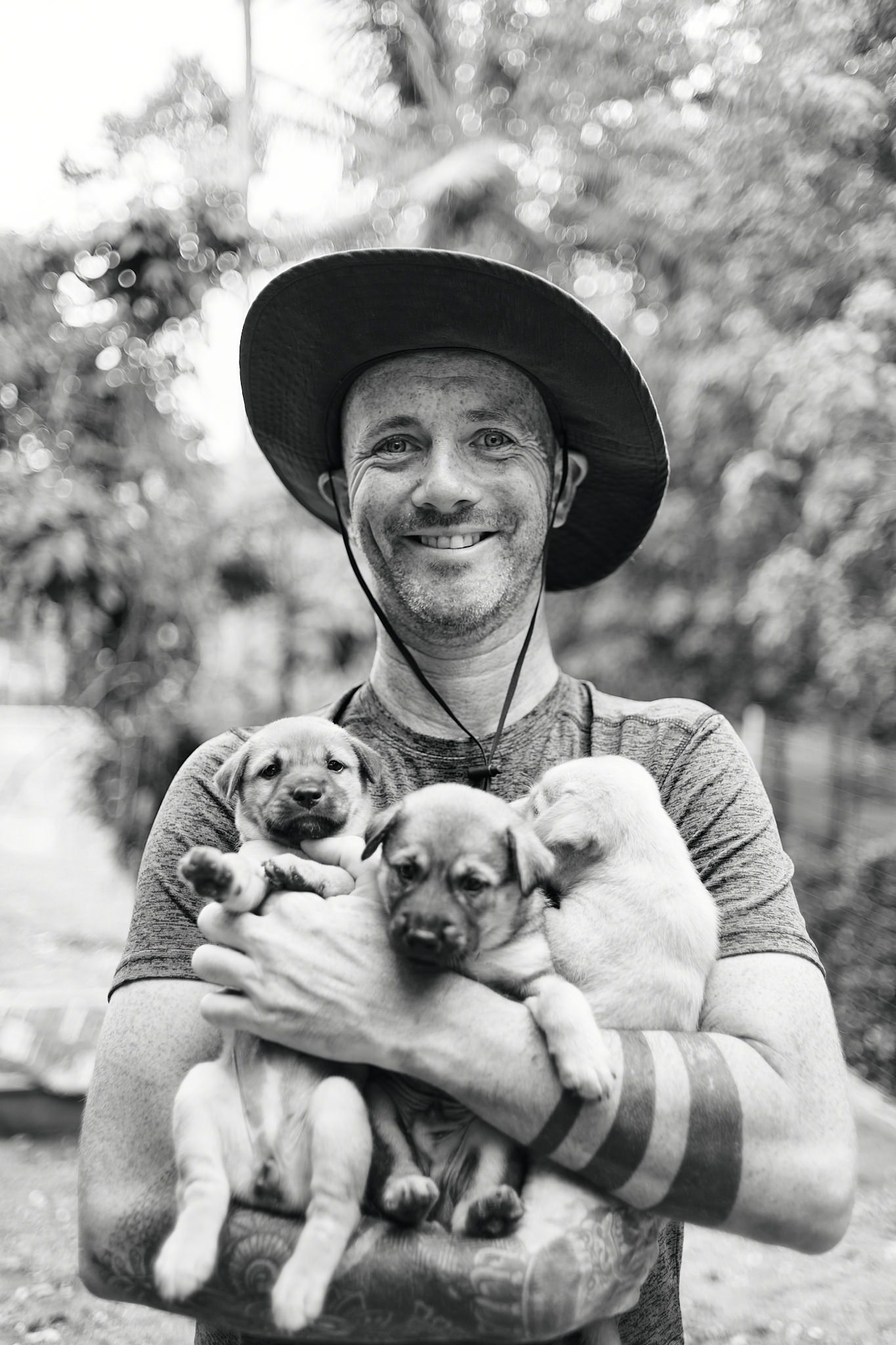 Niall Harbison holding three puppies at the rescue, black and white