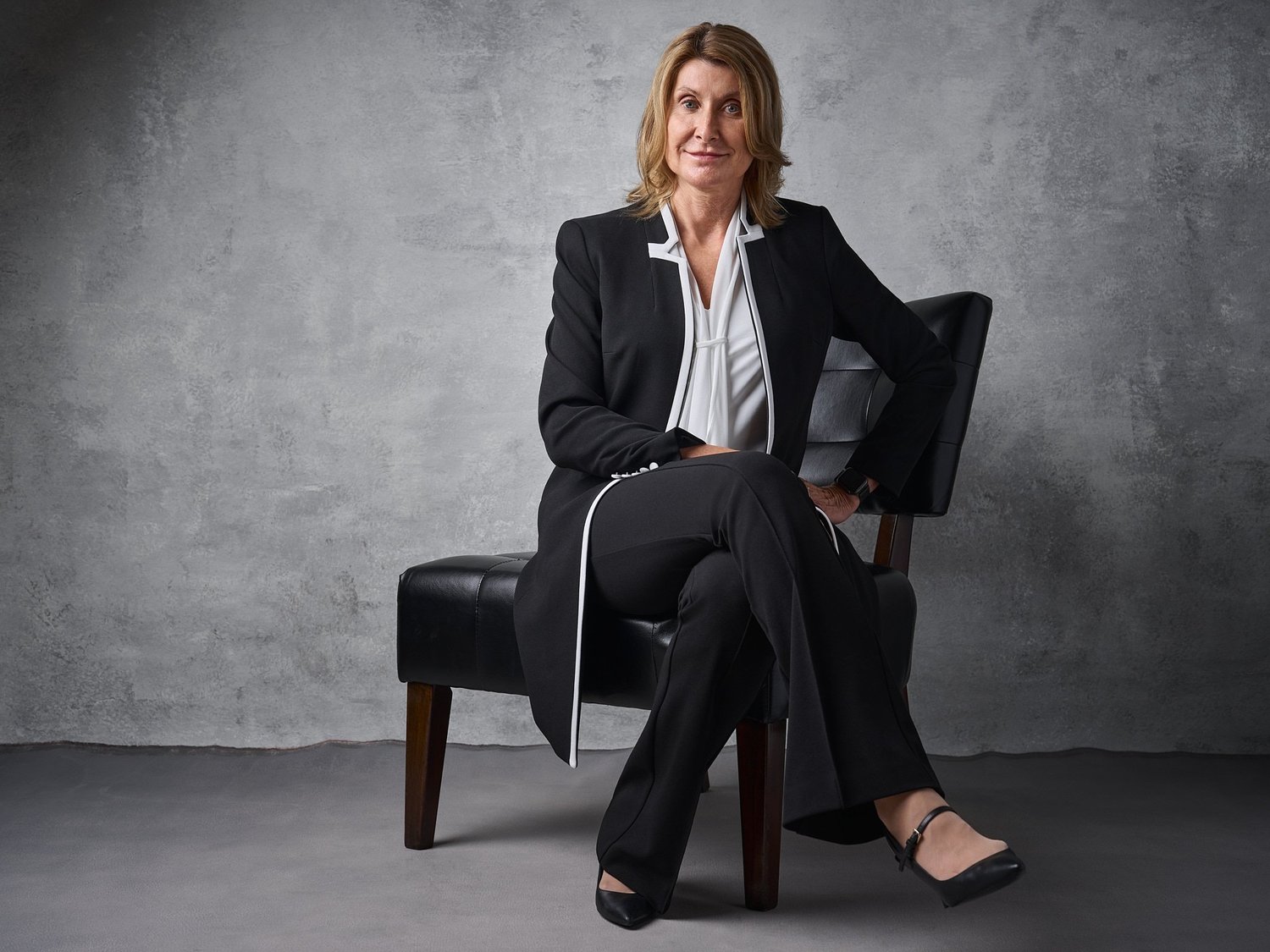 Color portrait of a woman in a black suit seated in a leather chair