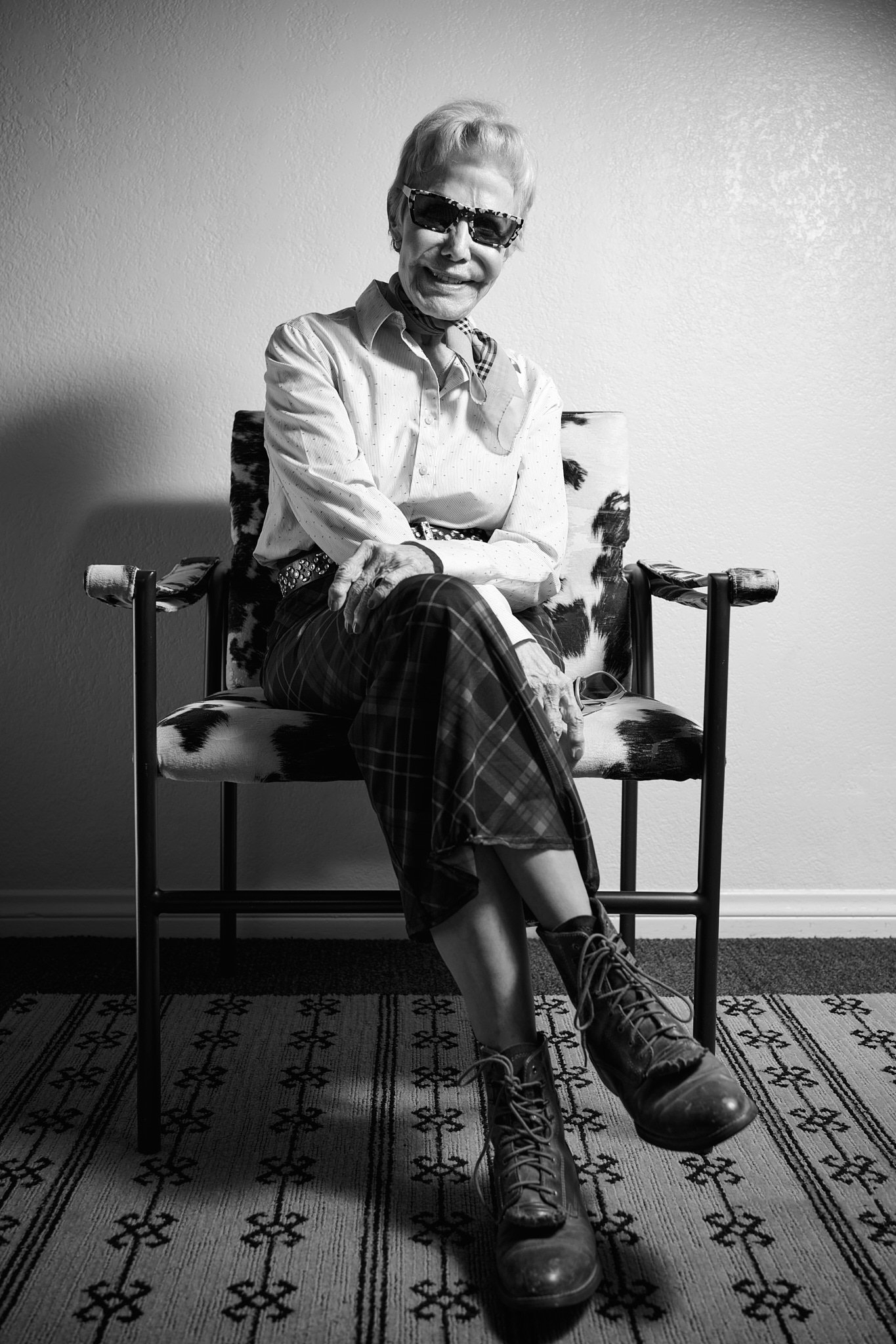 Actor seated in a cow-print chair, black and white
