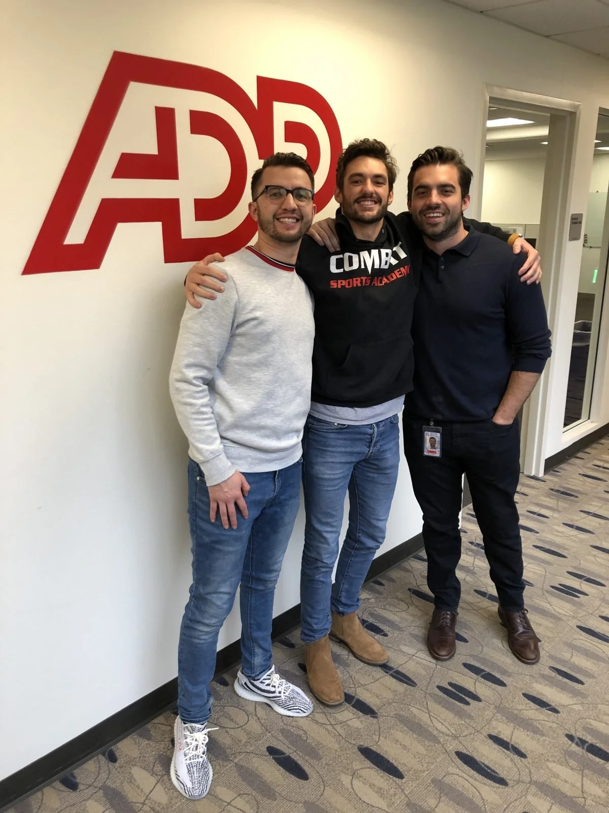 Logan with two ADP teammates under the ADP logo, 2018