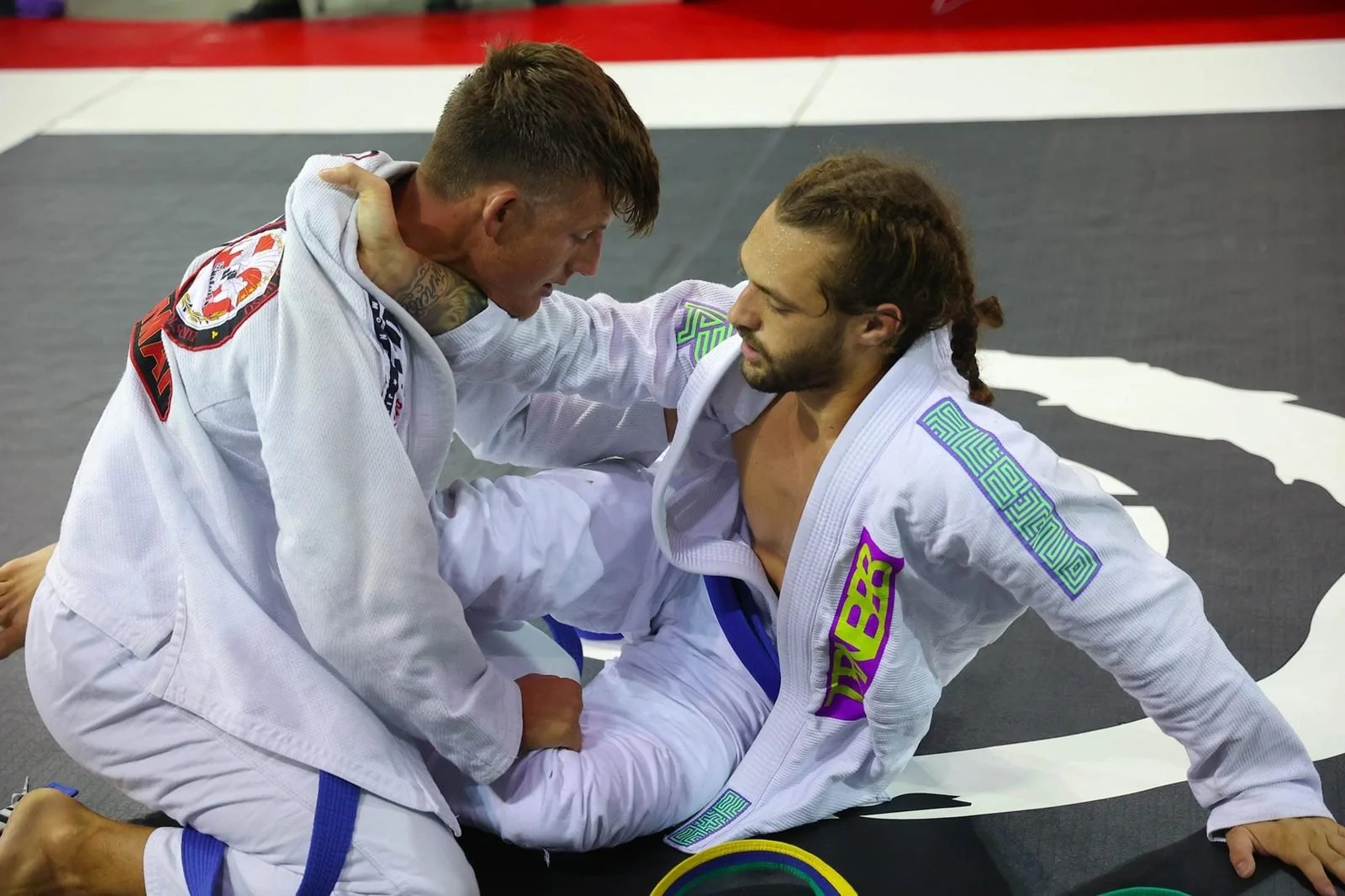 Logan grip fighting in a gi match on the tournament mats