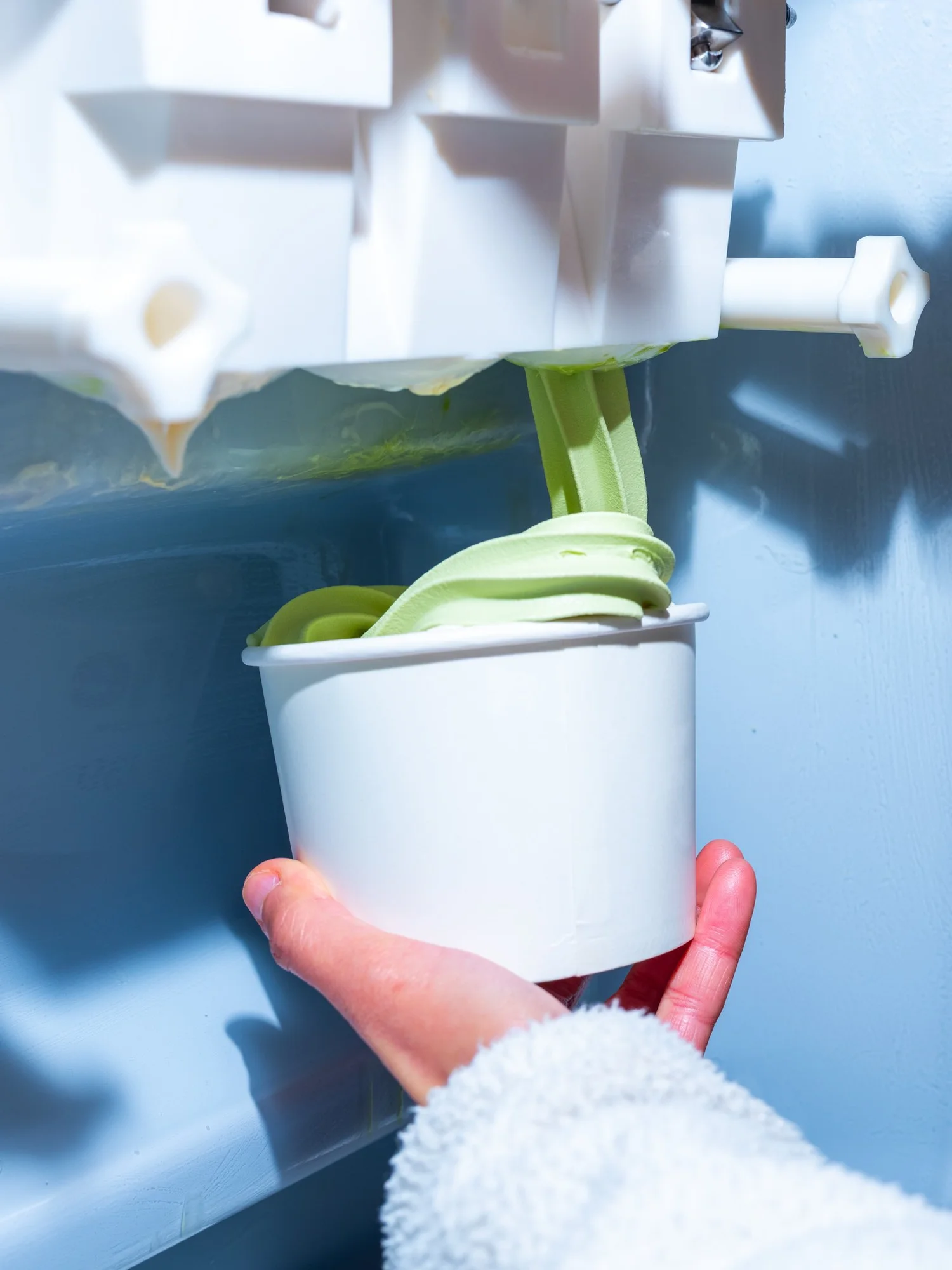 Matcha frozen yoghurt being poured into a cup
