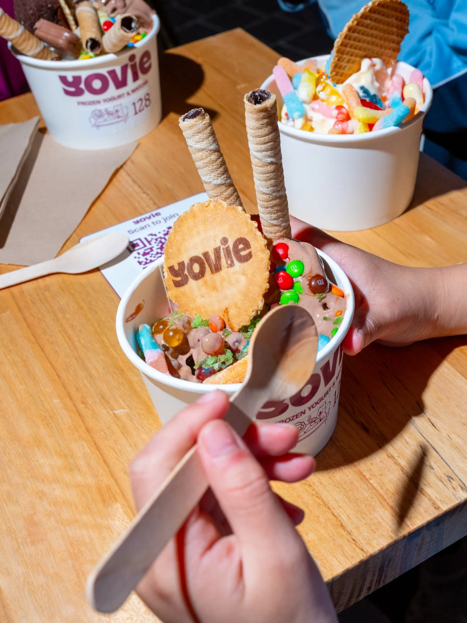 Colourful Yovie frozen yoghurt cups shared around a table
