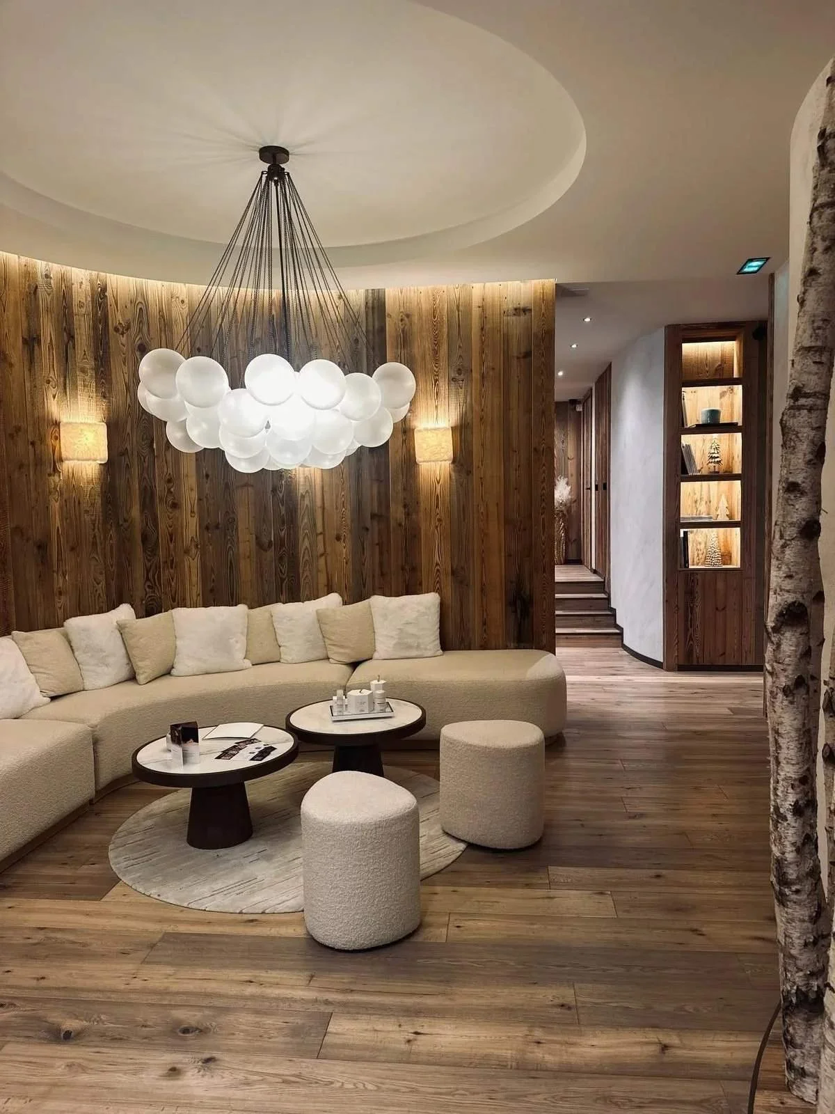 Salon lounge sous un lustre en boules de verre, canapé crème et bois