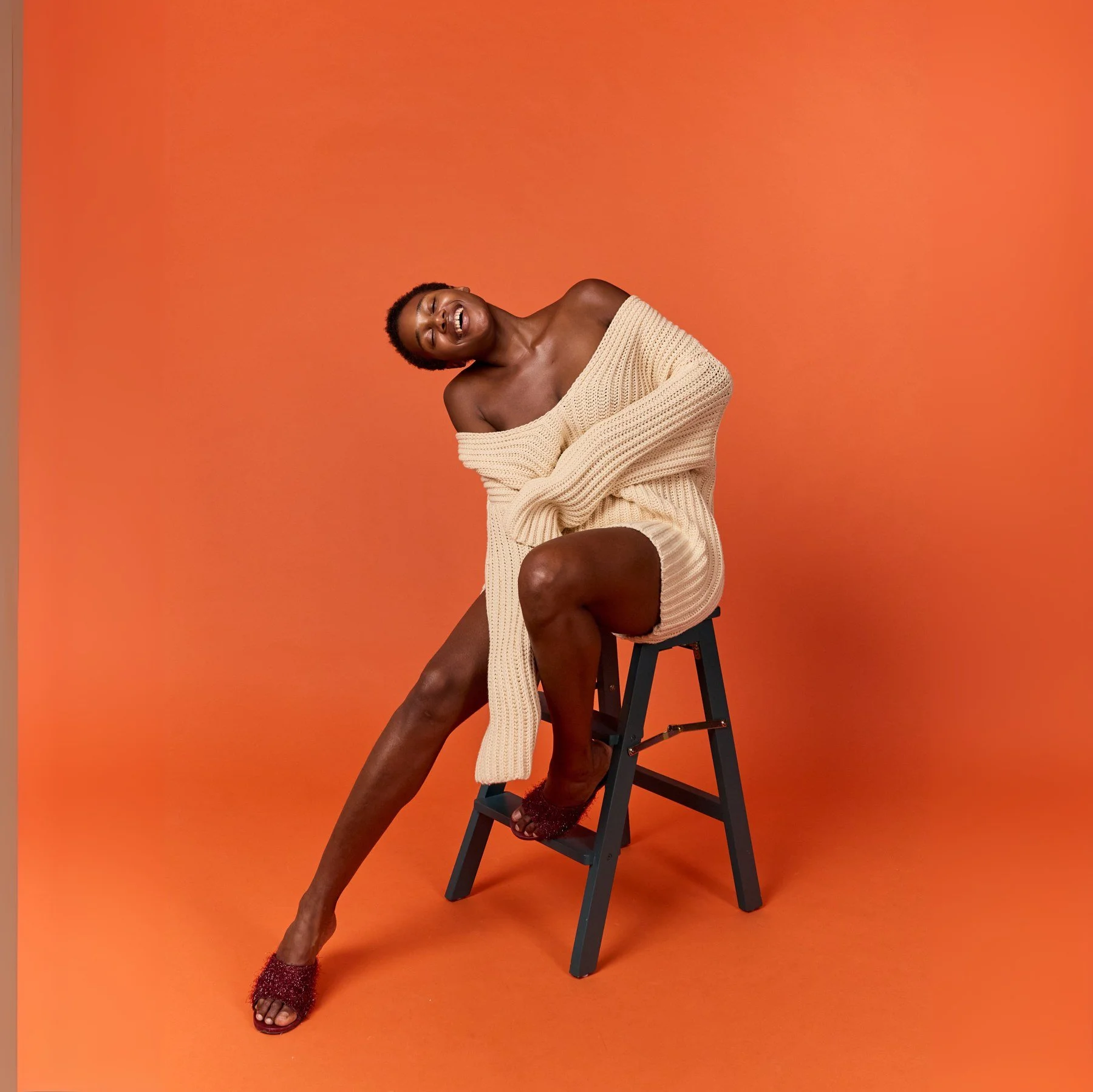 Fashion portrait in cream knitwear against an orange backdrop