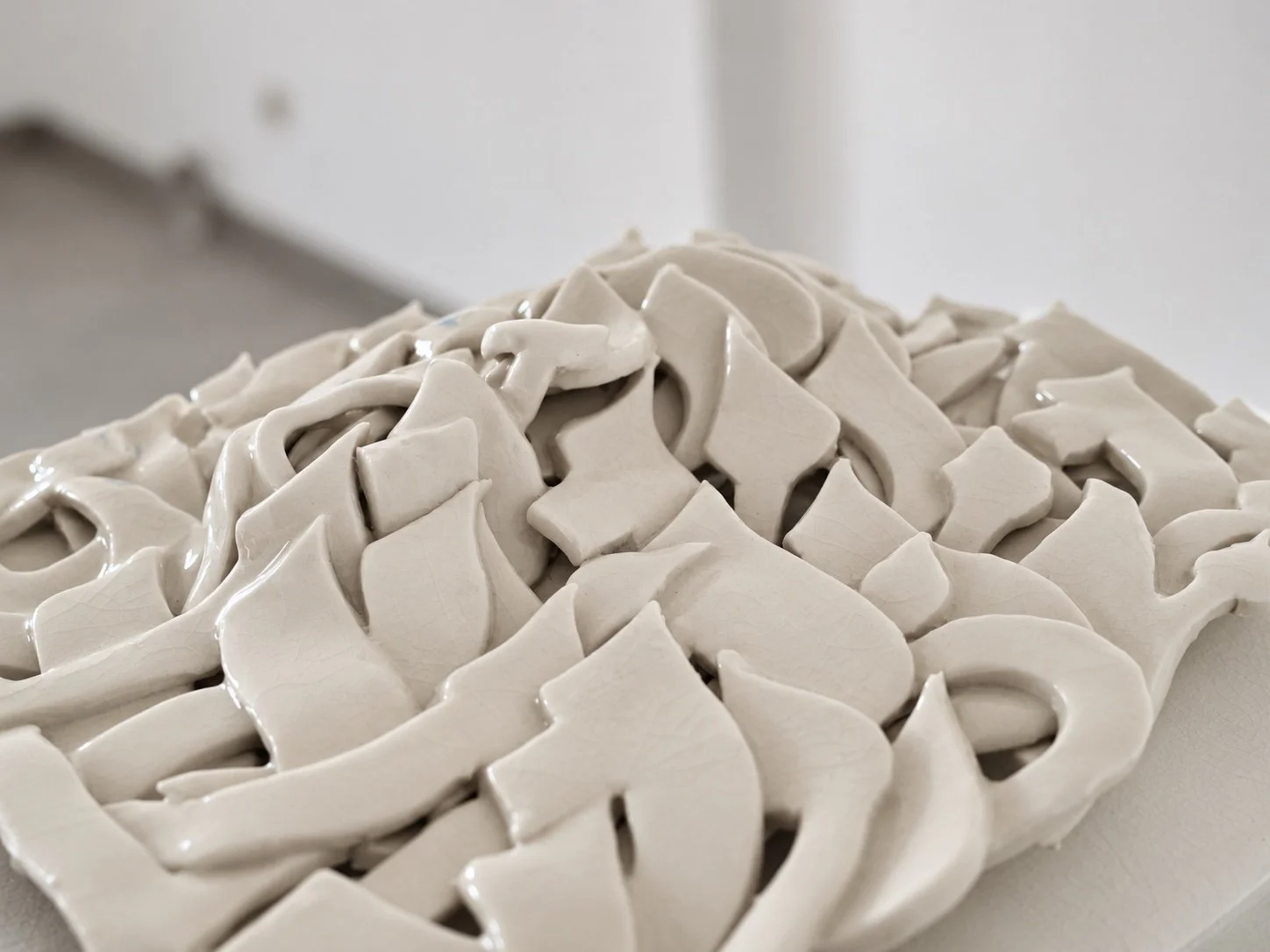 Close view of glazed white porcelain letter forms layered into a relief.