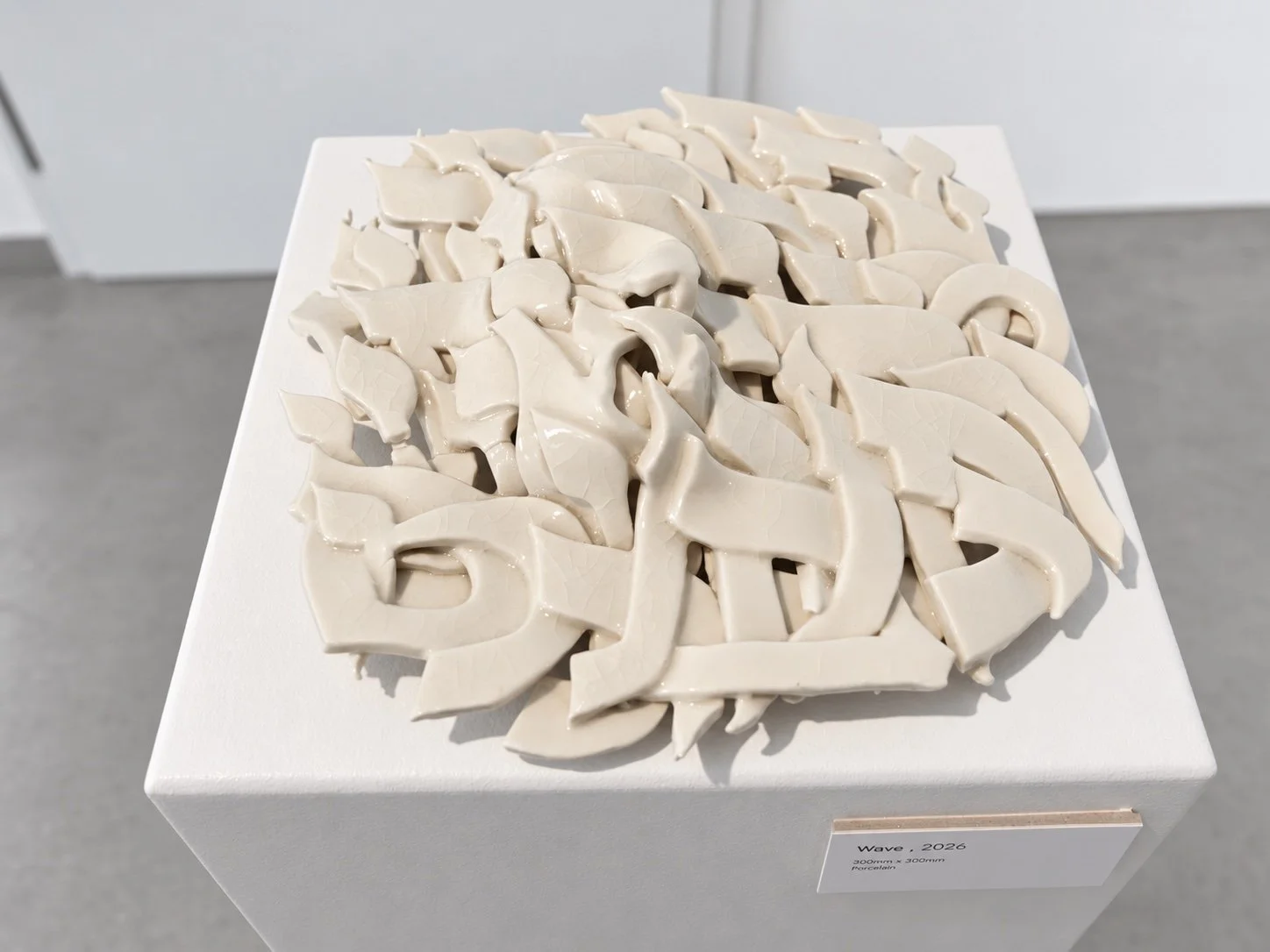 The porcelain relief on a white plinth, with its label at the lower right.