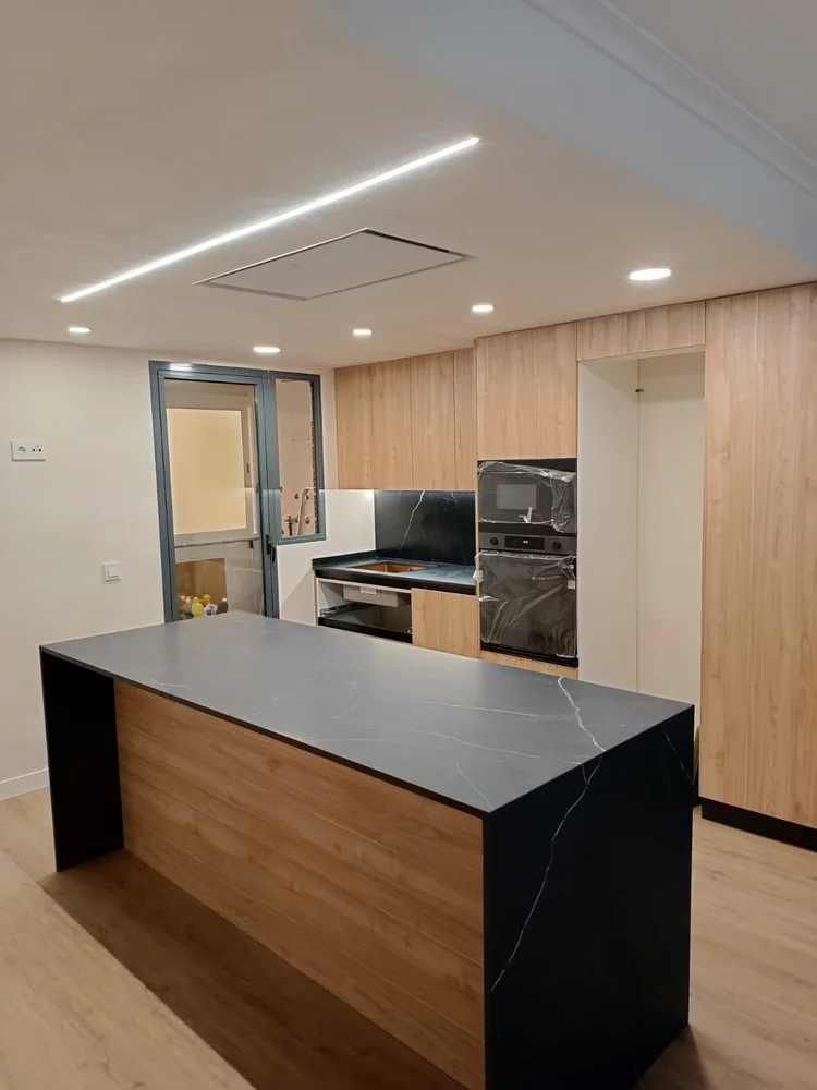 Cocina con columnas de madera e isla negra veteada