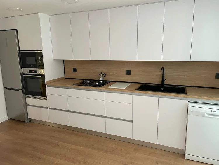 Cocina blanca con encimera y frontal efecto madera y fregadero negro