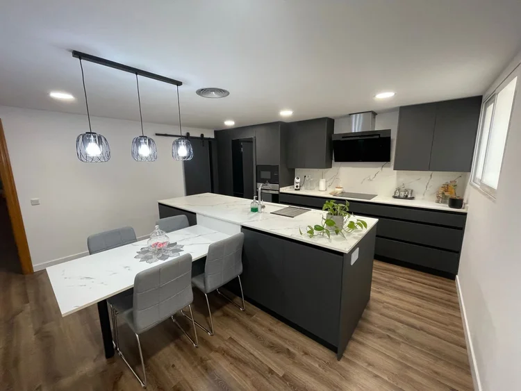 Cocina gris antracita con isla, mesa integrada y lámparas colgantes