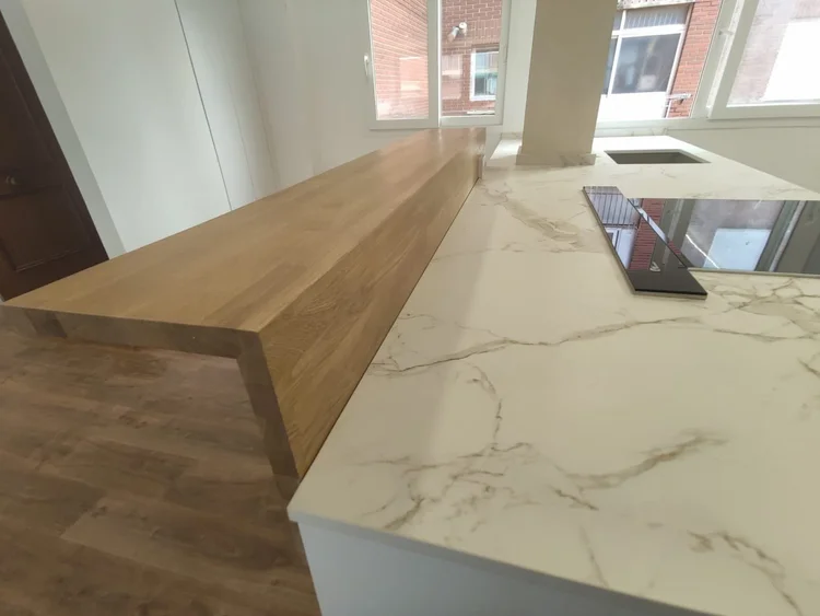 Detalle de encimera porcelánica efecto mármol y barra de madera