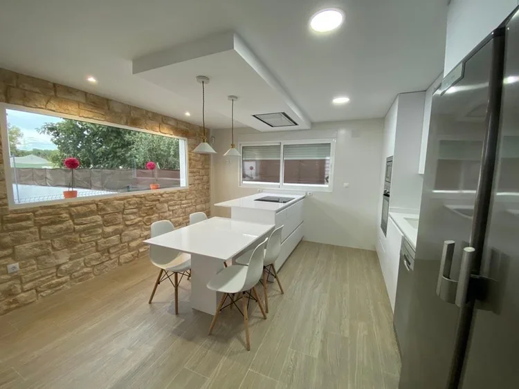 Cocina abierta con isla, mesa y pared de piedra decorativa