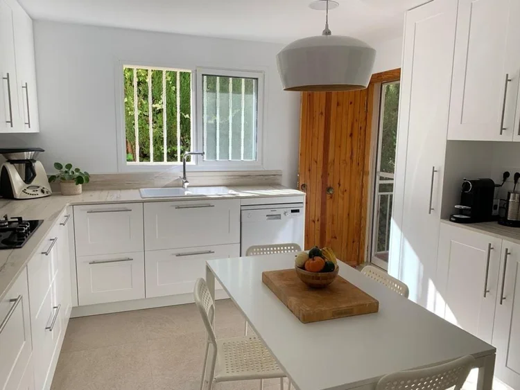 Cocina blanca de estilo clásico con ventana y mesa