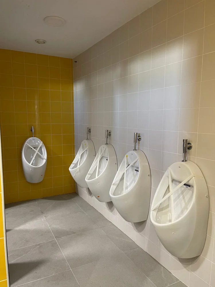Batería de urinarios con alicatado amarillo y blanco
