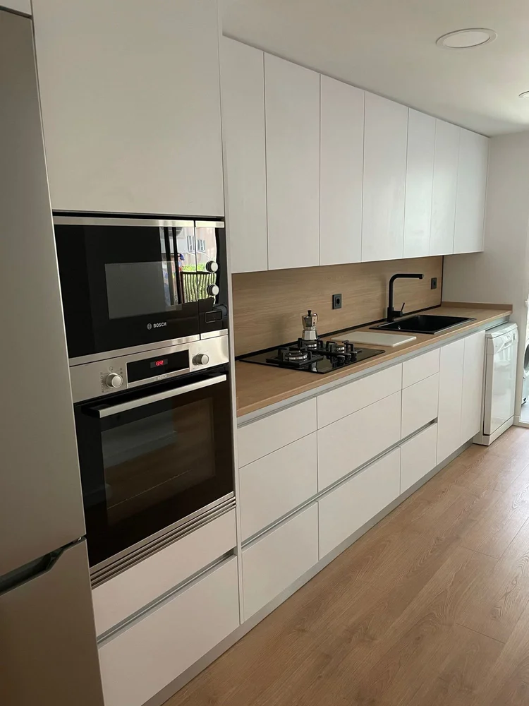 Cocina blanca con encimera de madera y columna de hornos