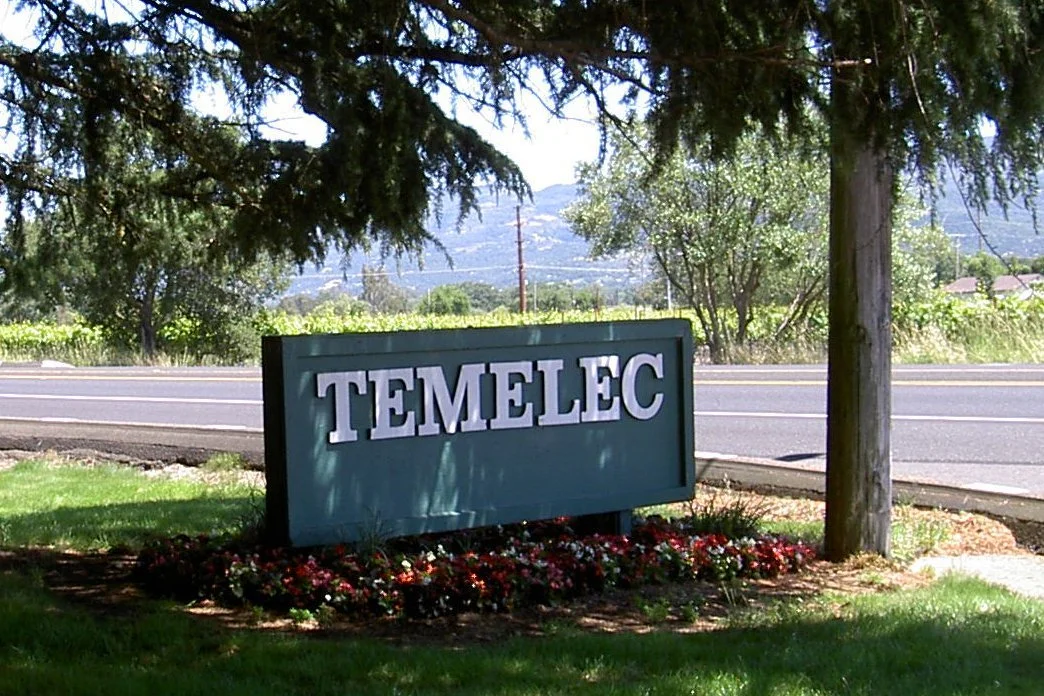 Temelec community entrance sign with flowers beneath a large tree