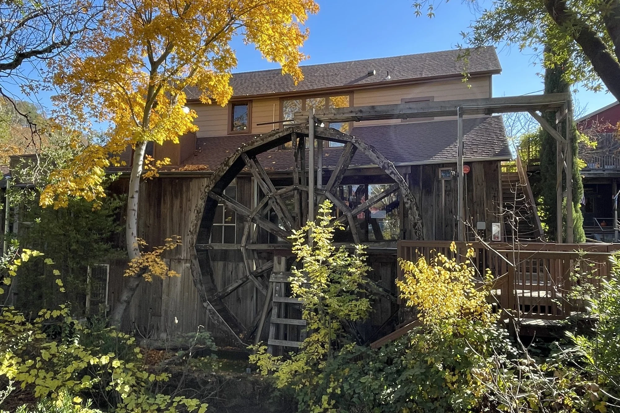 Historic wooden waterwheel and mill building at The Mill in Glen Ellen with autumn foliage