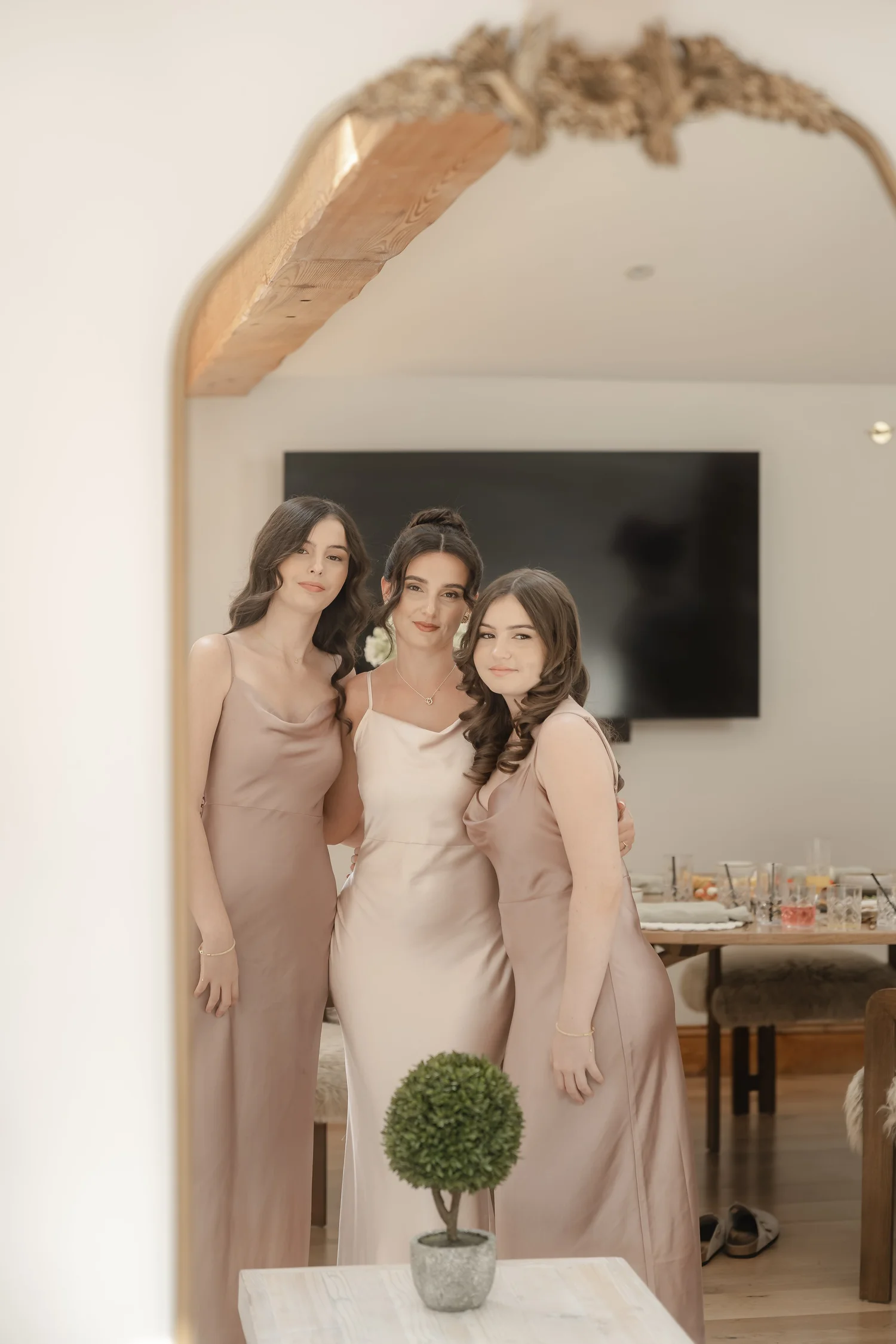 Three women reflected in a mirror after having their makeup done by Carrie Jane