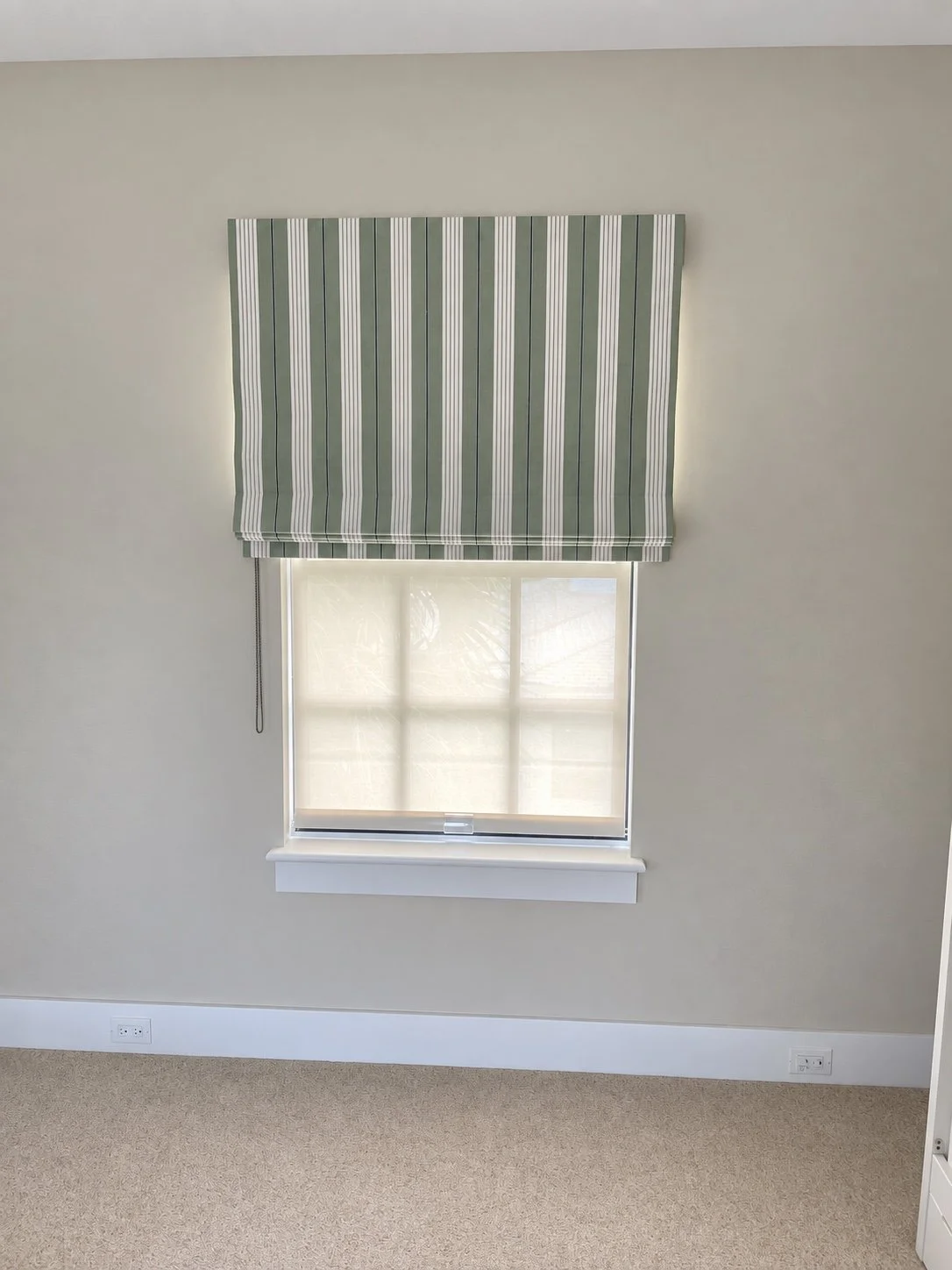 Green striped Roman shade fitted above a window