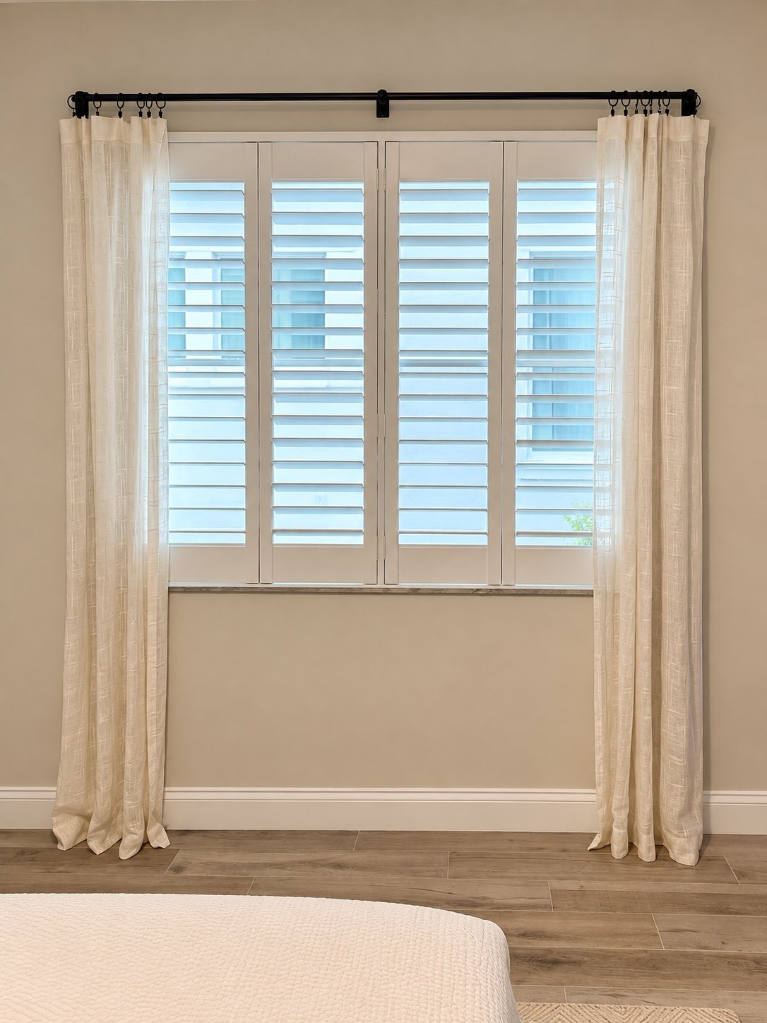 Plantation shutters layered with sheer side drapery