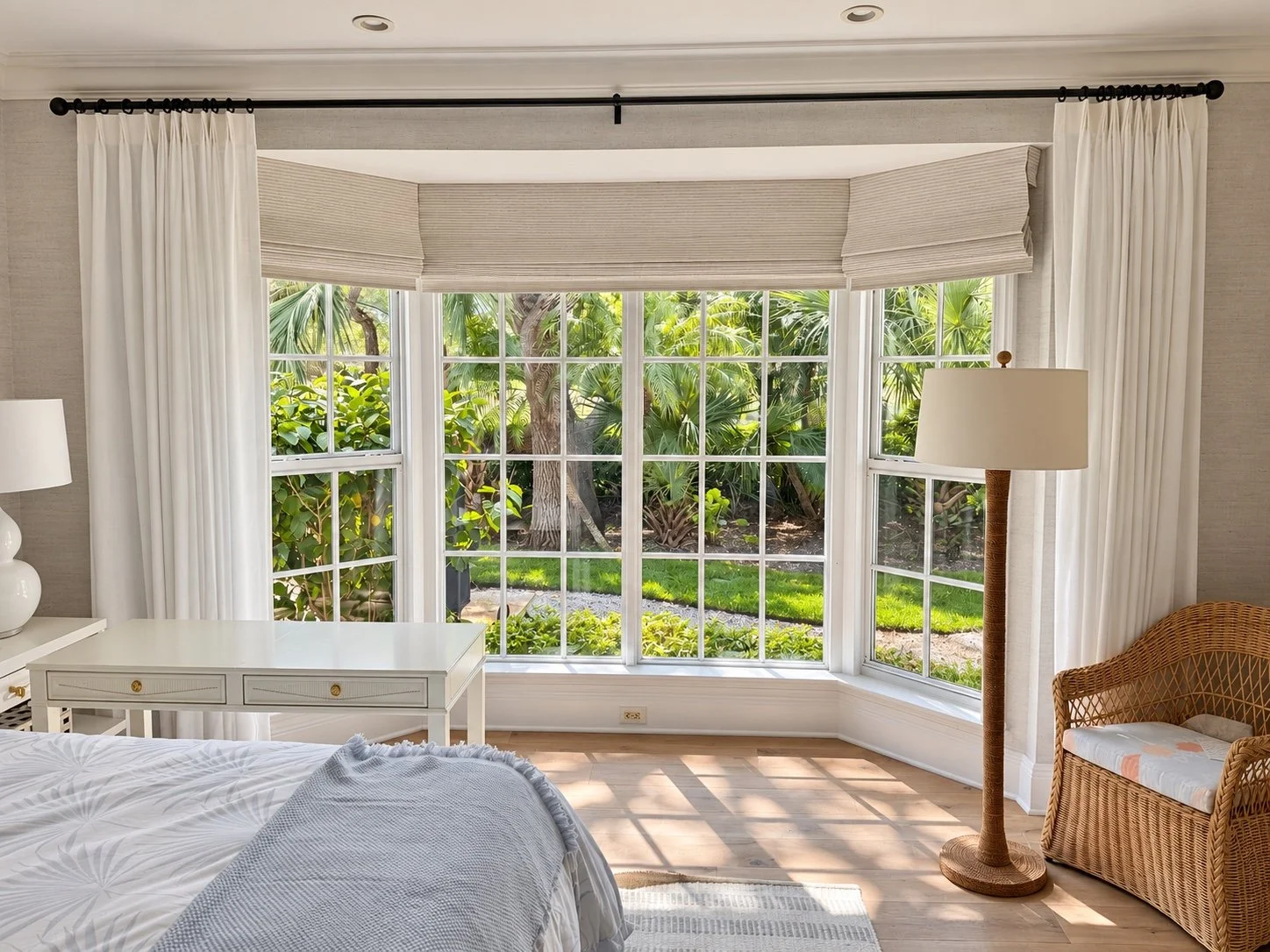 Roman shades layered with full-length side drapery around a bay window