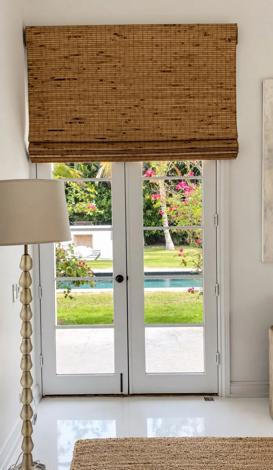 Woven wood Roman shade above white French doors