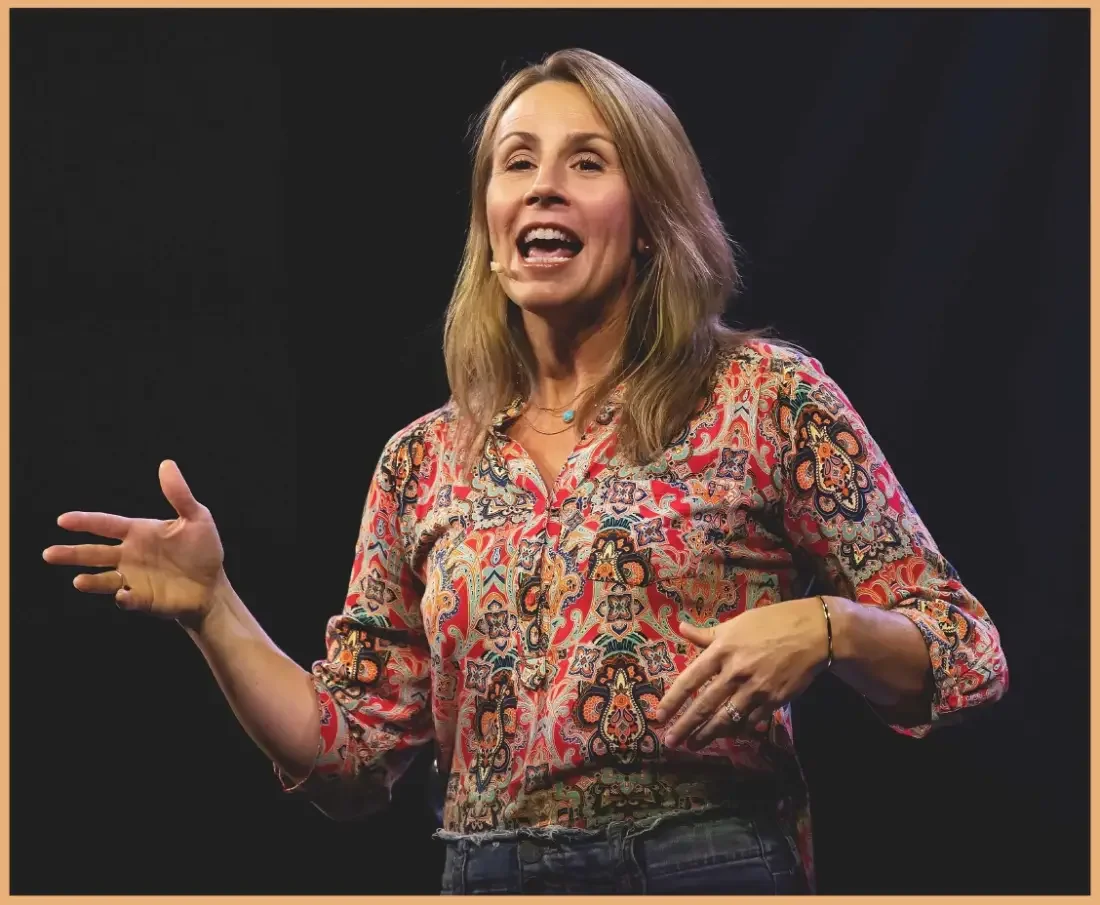 Alli Patterson speaking on stage with a headset microphone
