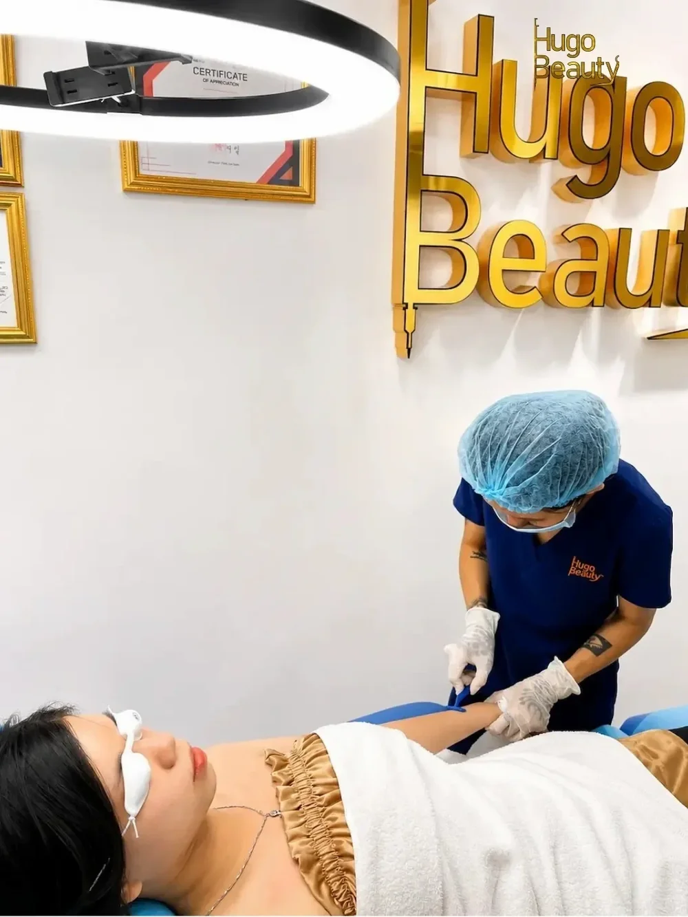 A specialist doing a diode laser hair removal session on a client's stomach at Hugo Beauty