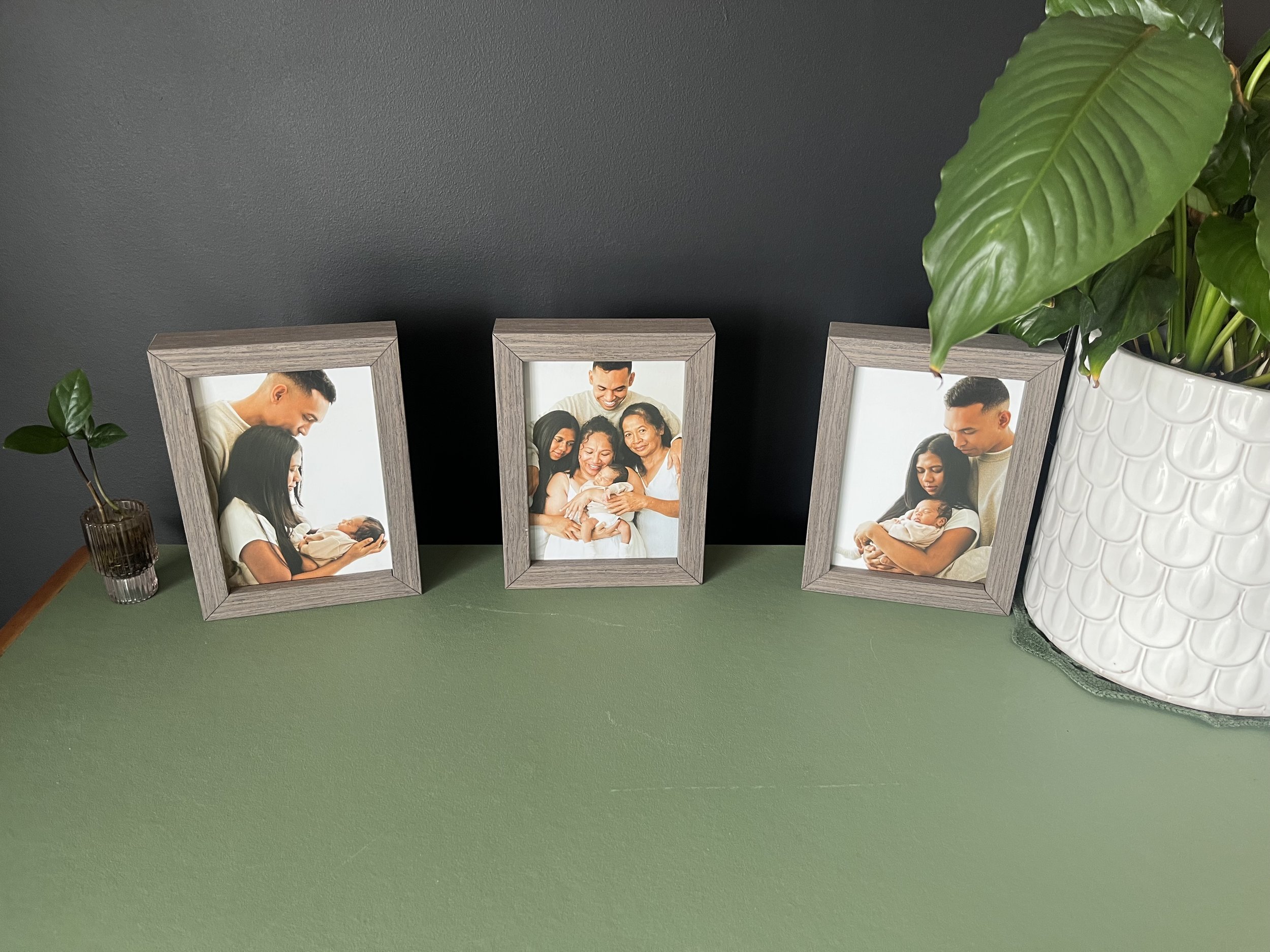 Three framed 5x7 family portraits on a green sideboard