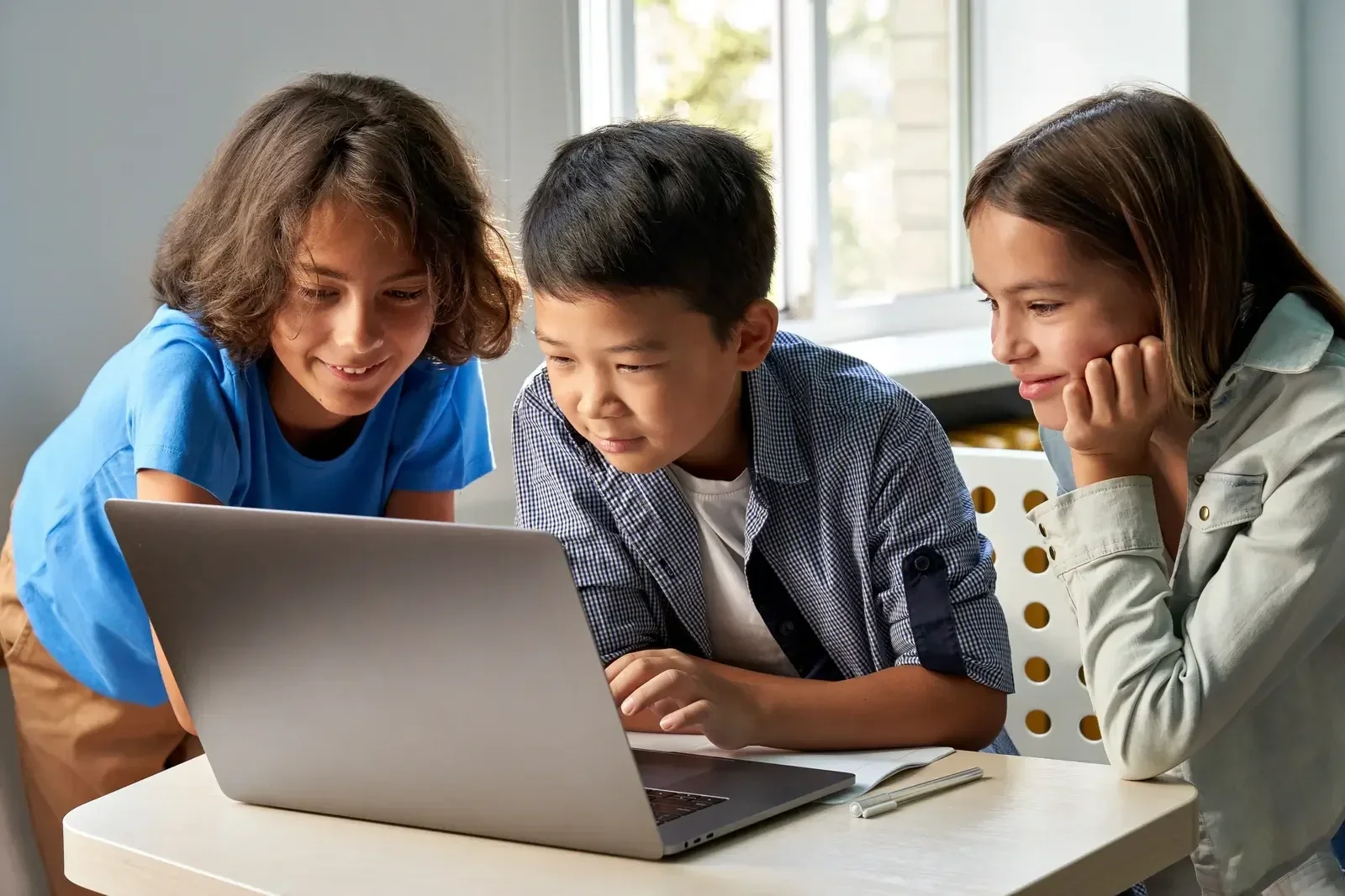 Three kids collaborating on a coding project around a laptop — Aprise Learning Introduction to Coding course for Grades 5–8