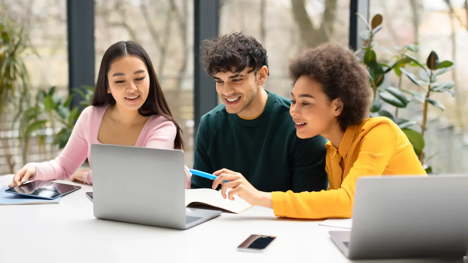 Three high school students collaborating on a coding project around a laptop — Aprise Learning Python Programming course for Grades 9–12