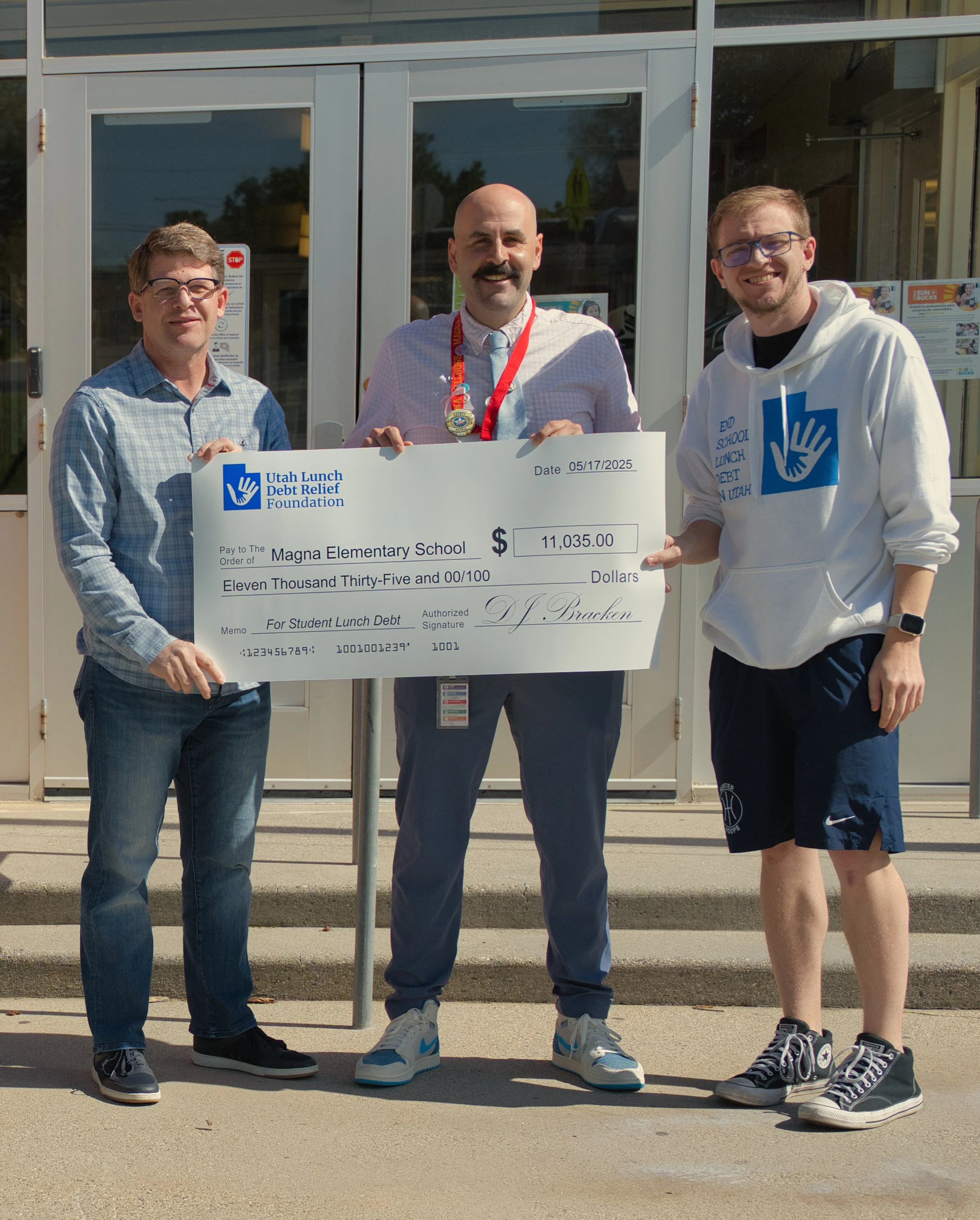 Founder and two volunteers holding a Utah Lunch Debt Relief Foundation check for student lunch debt.