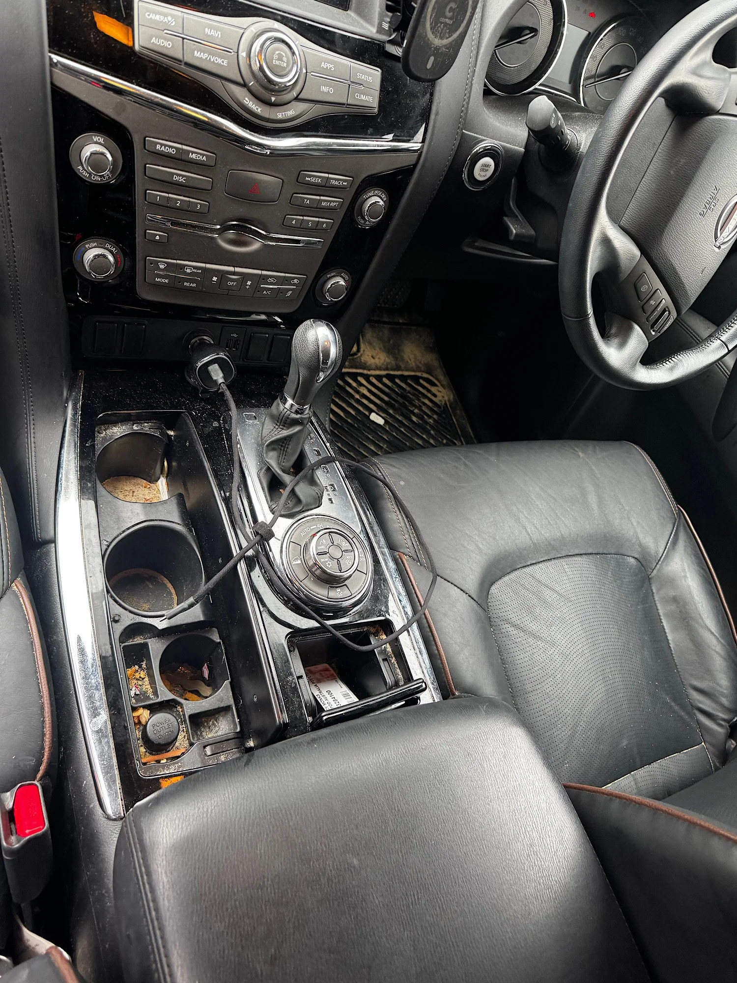 Dirty center console with crumbs and debris inside Nissan Patrol Warrior before interior detailing