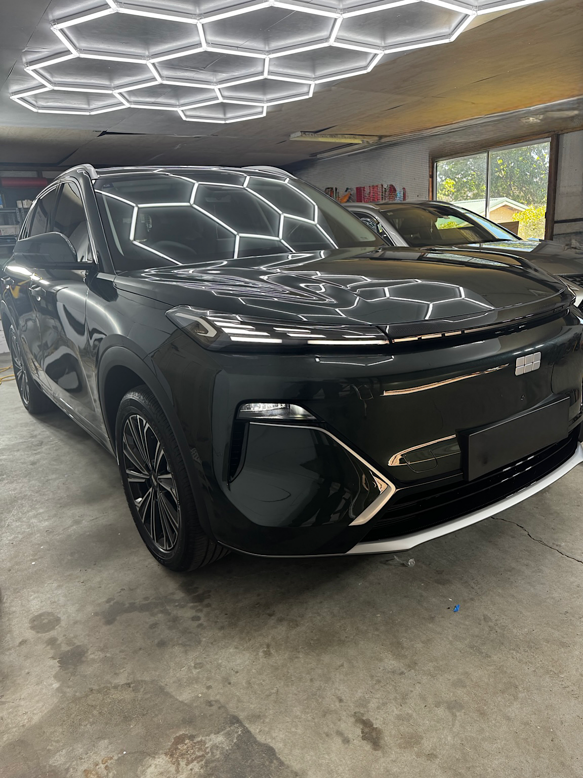 Front three-quarter view of the dark green Geely Starray EM-i inside RD's Wyong studio