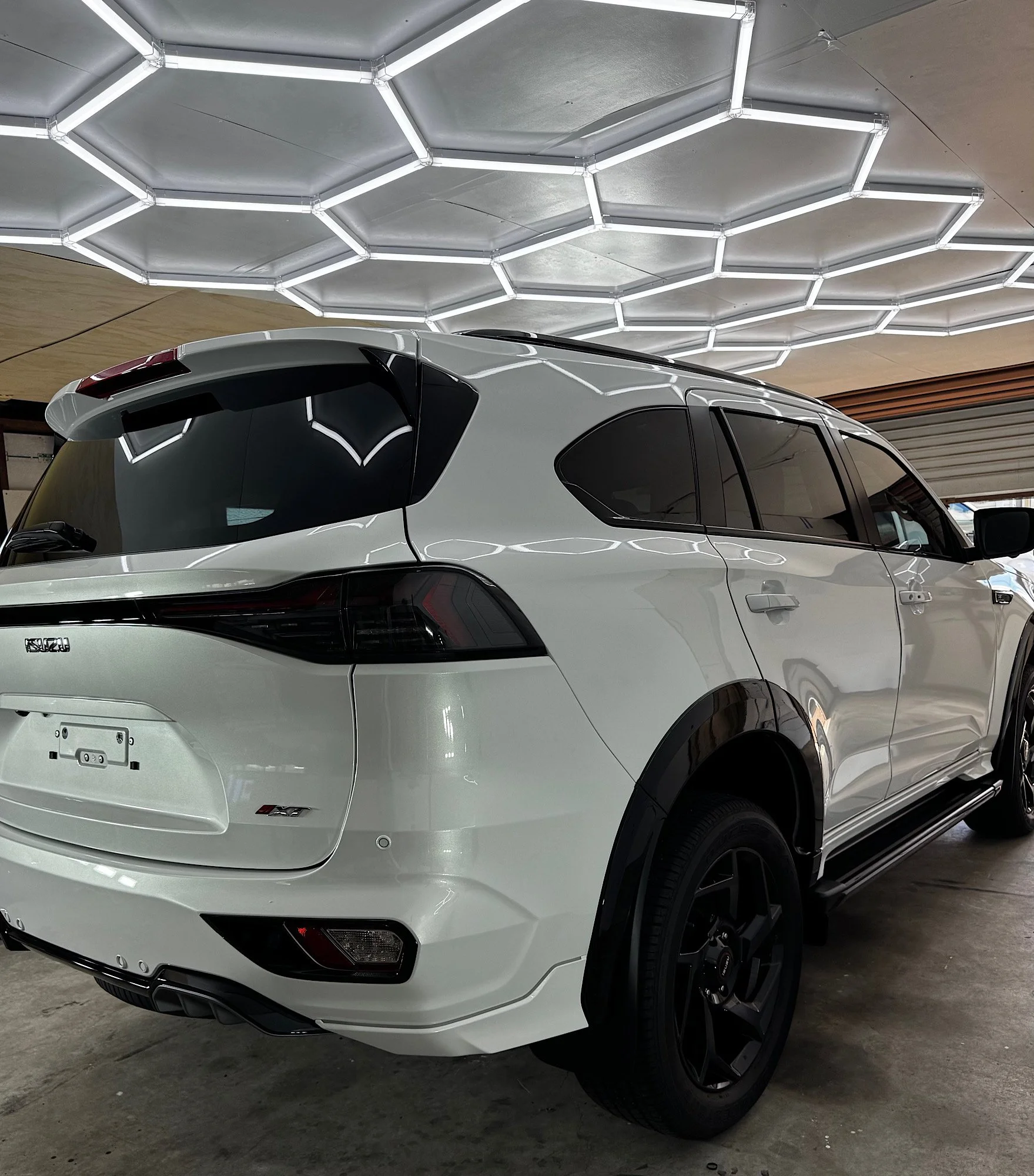 Rear three-quarter view of a 2026 Isuzu MU-X showing tinted side and rear windows and ceramic-coated white paint at our Wyong studio