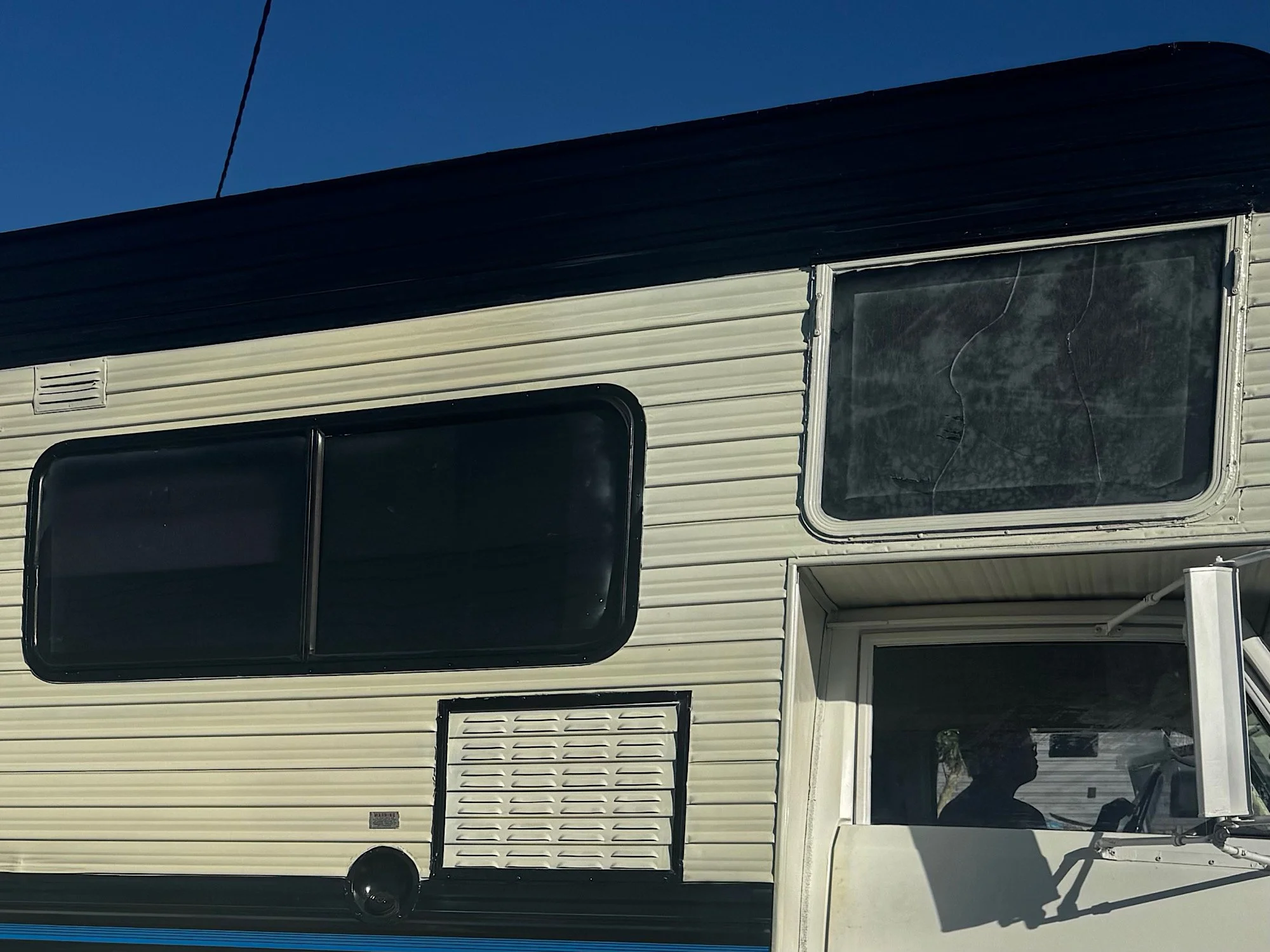 Side windows of a Winnebago motorhome before silver privacy film installation