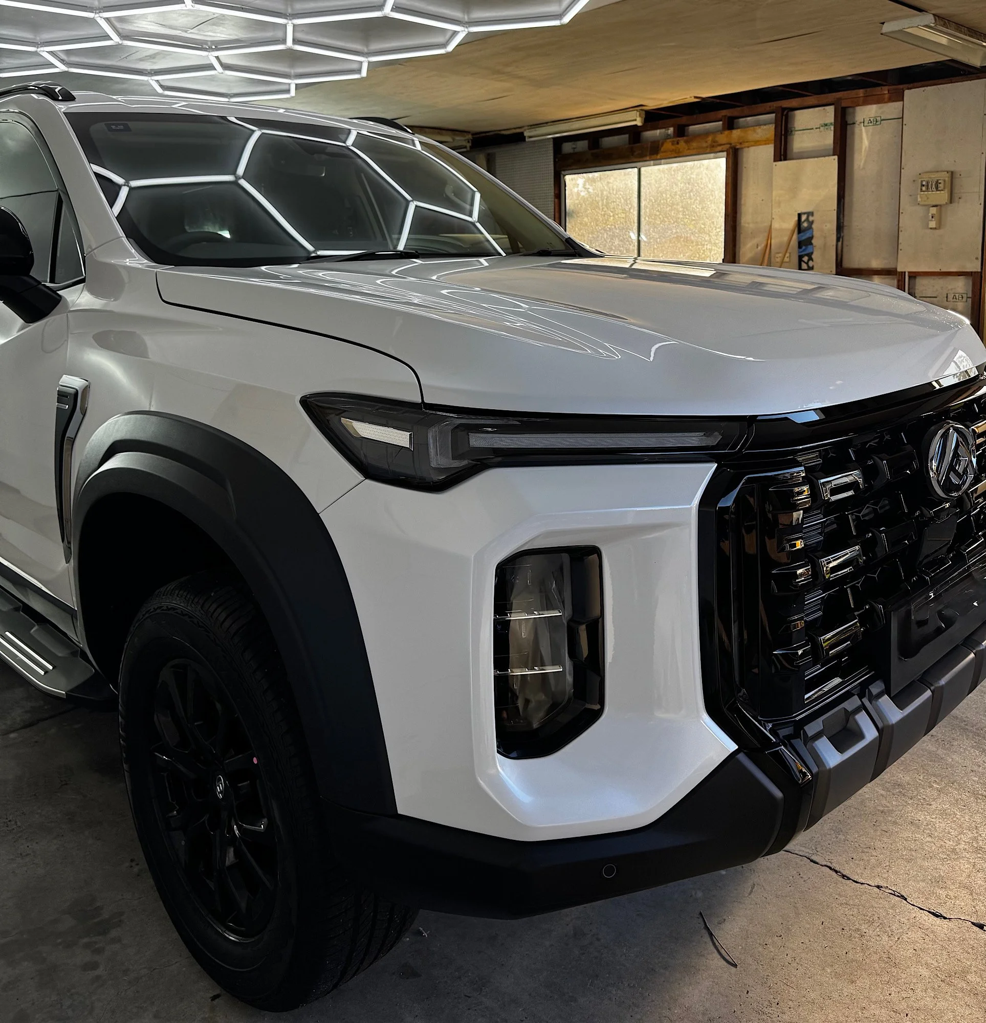 Close-up front three-quarter view of the white 2026 LDV D90 showing the grille, bonnet reflections and black front alloy wheel after ceramic coating