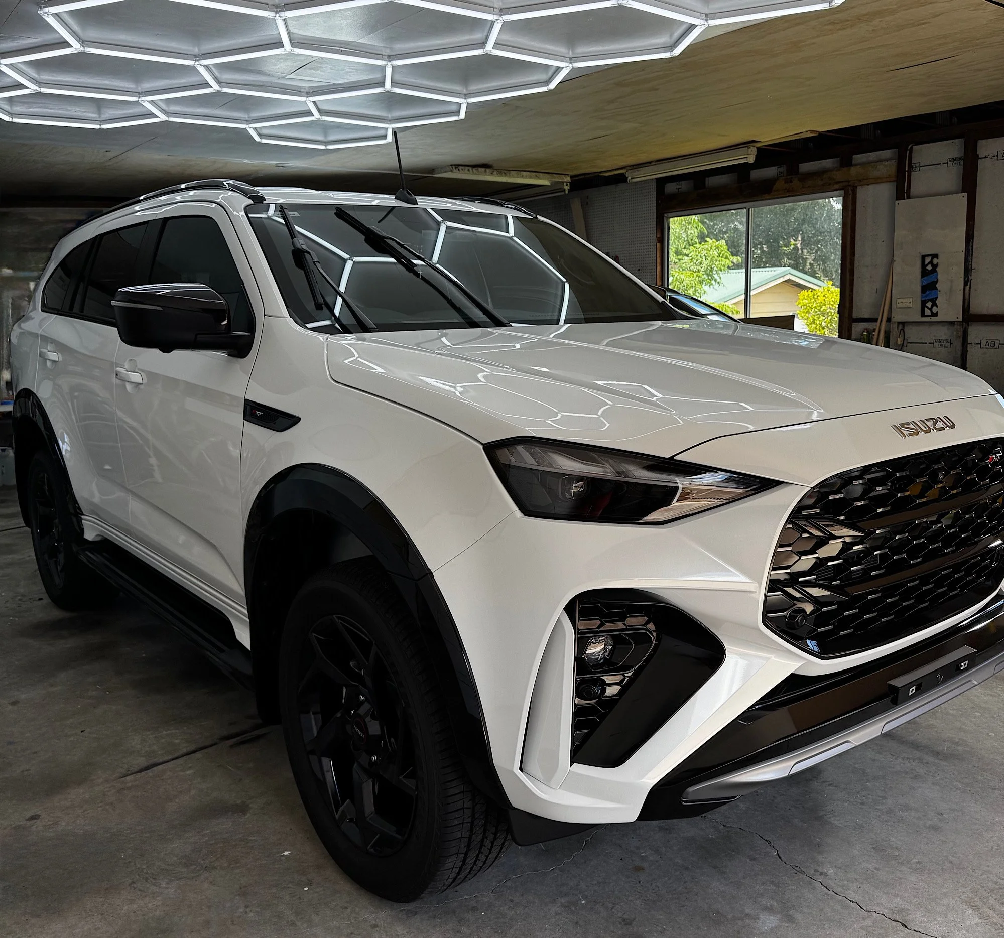 White 2026 Isuzu MU-X showing its finished bonnet, side panels and tinted windows at RD Mobile Car Detailing in Wyong