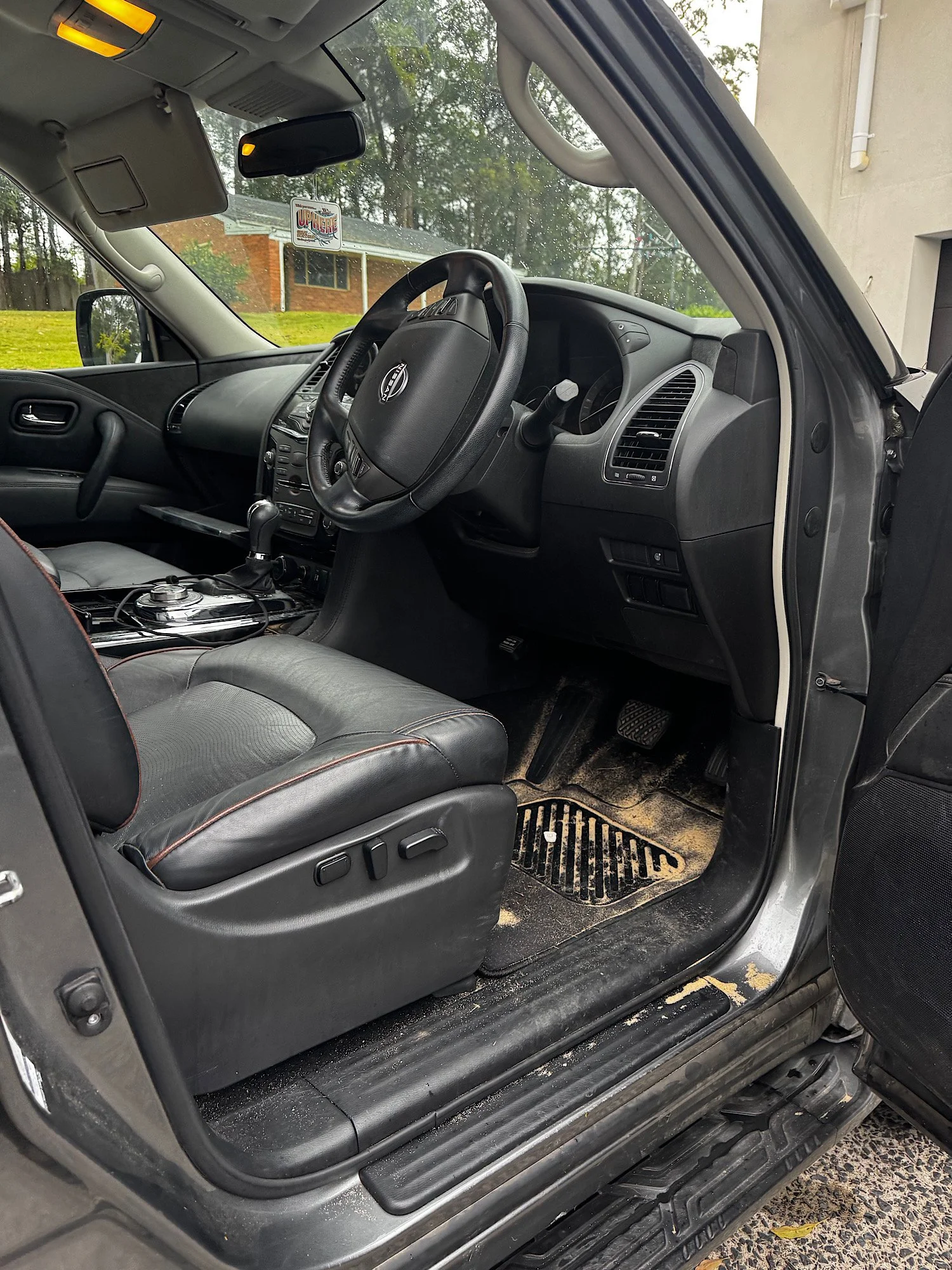 Driver footwell and seat with sand and dirt buildup inside Nissan Patrol Warrior before detailing