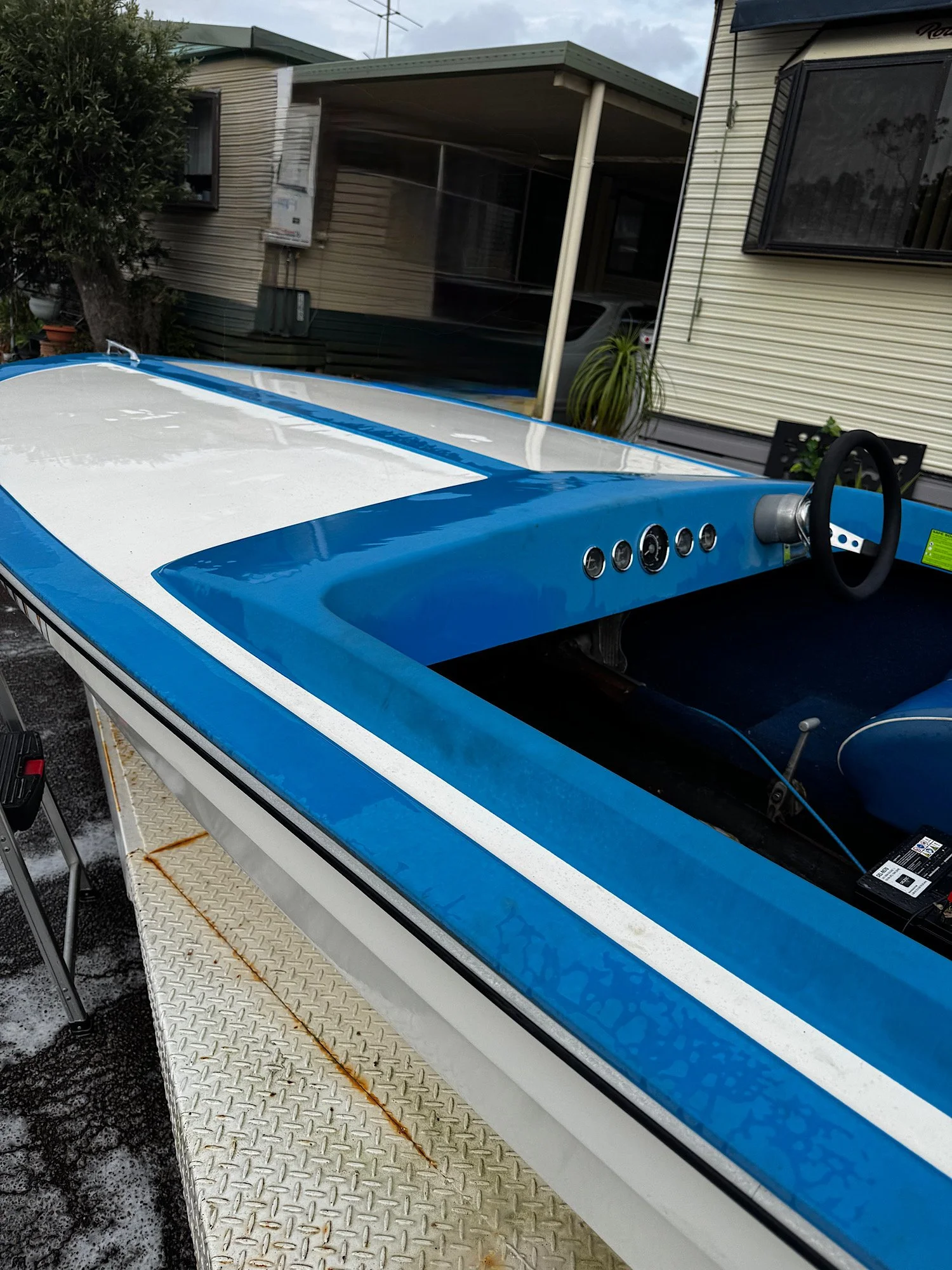 Blue-and-white boat before paint correction, showing visible spotting across the upper surfaces.