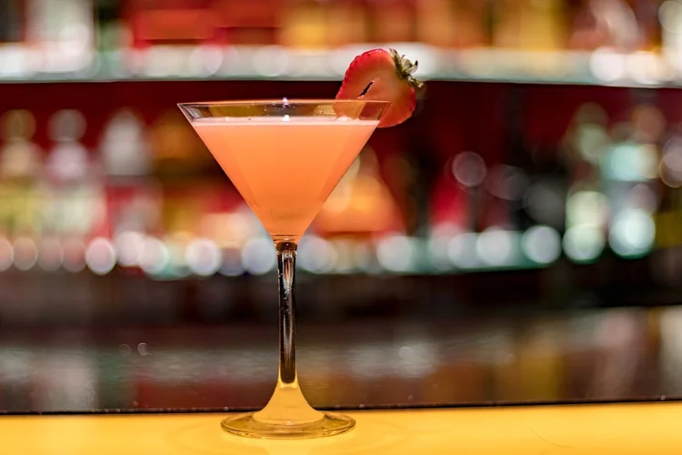 Pink strawberry Bellini in a cocktail glass at a bar