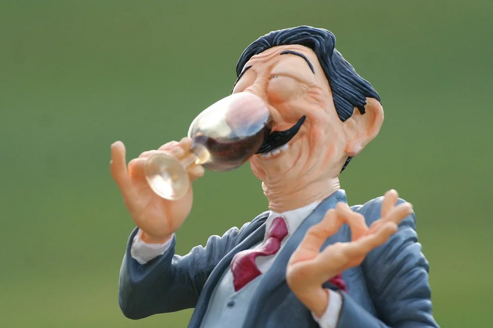 Figurine of a man in a suit tasting a glass of red wine