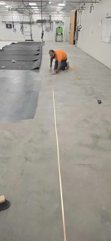 Installer placing grounding strips over the prepared substrate for static-dissipative flooring.