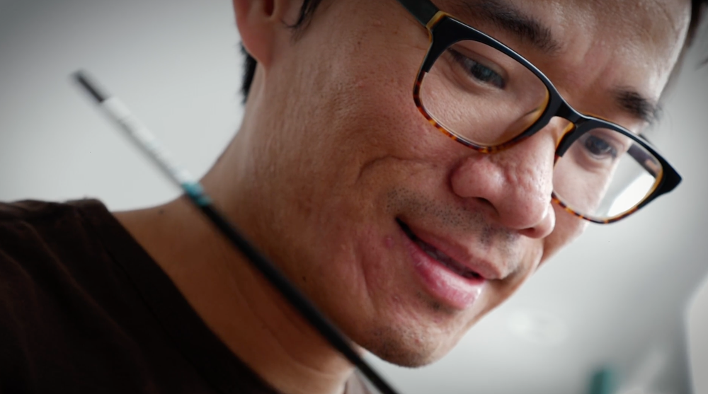 Bao Pham smiling with a paintbrush in hand