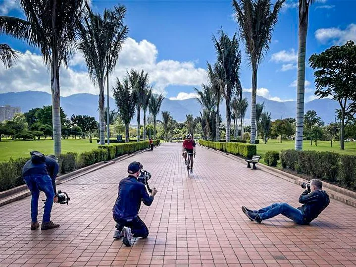 Crew getting a low-angle shot on a palm-lined plaza