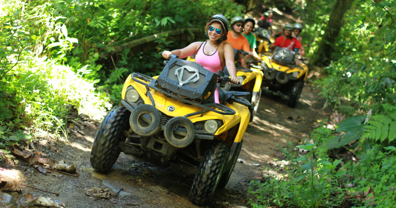 A woman smiles as she drives her ATV down a dirt path